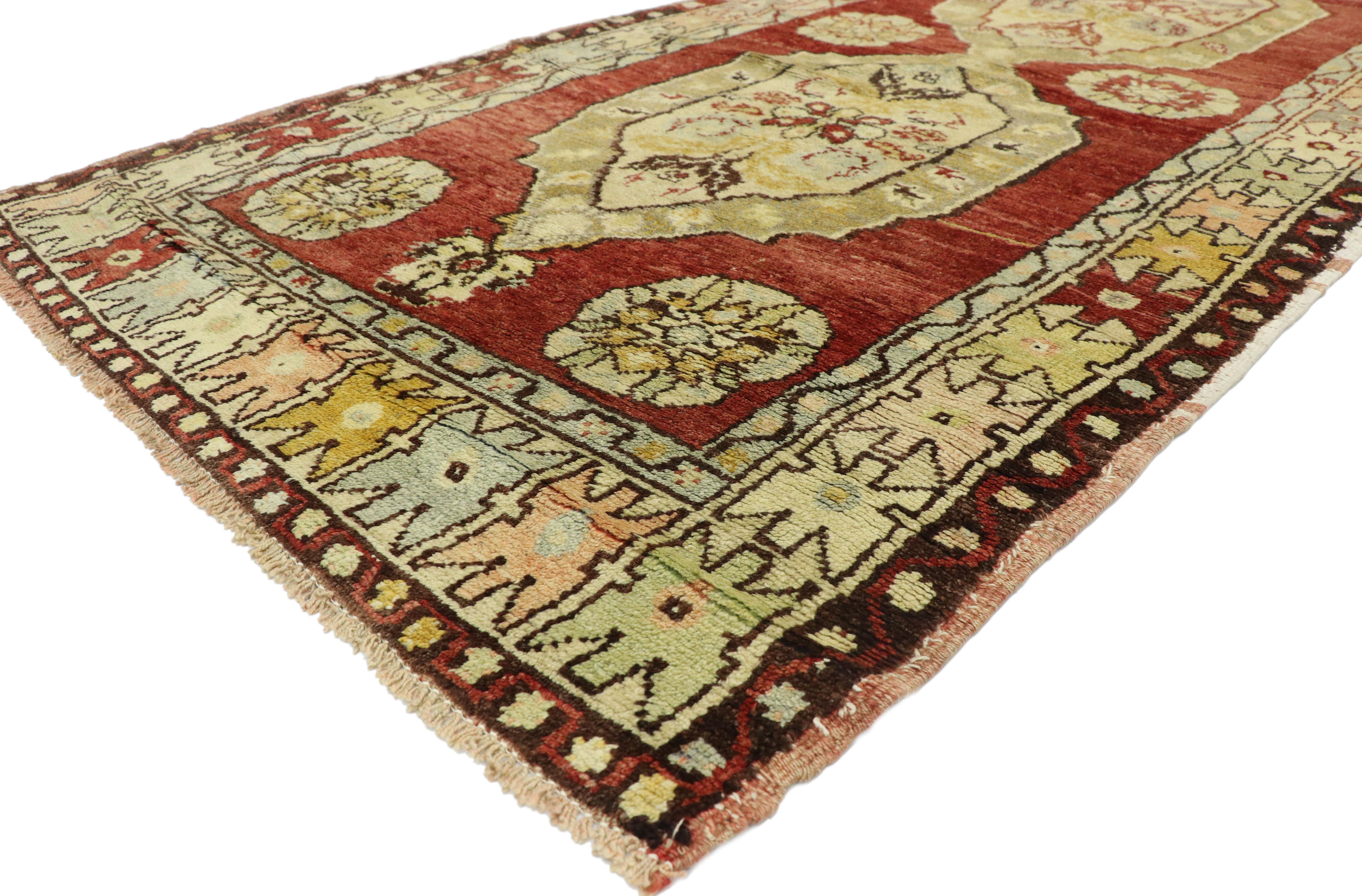 52121, rustic style vintage Turkish Oushak runner, hallway runner. This hand knotted wool vintage Turkish Oushak runner features three connected hexagonal medallions capped with palmette pendants spread across an abrashed red field. Each medallion