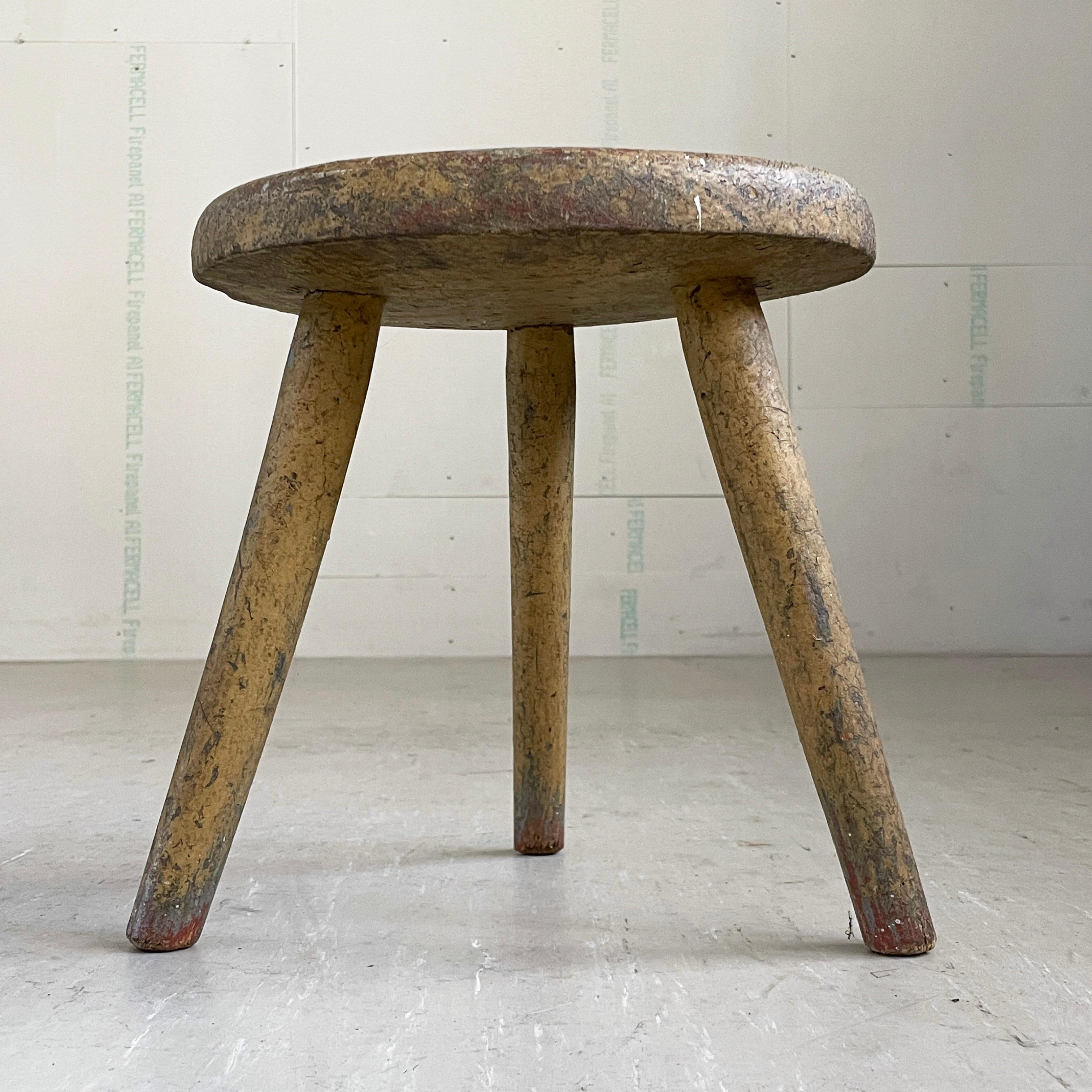 Vintage rustic Swiss farmhouse milking stool. Intensively patinated with multiple layers of crackled paintwork making it unique. Wooden construction with tripod legs. Slight tilt to seat for milking. Estimated to be from to the end of the 19th