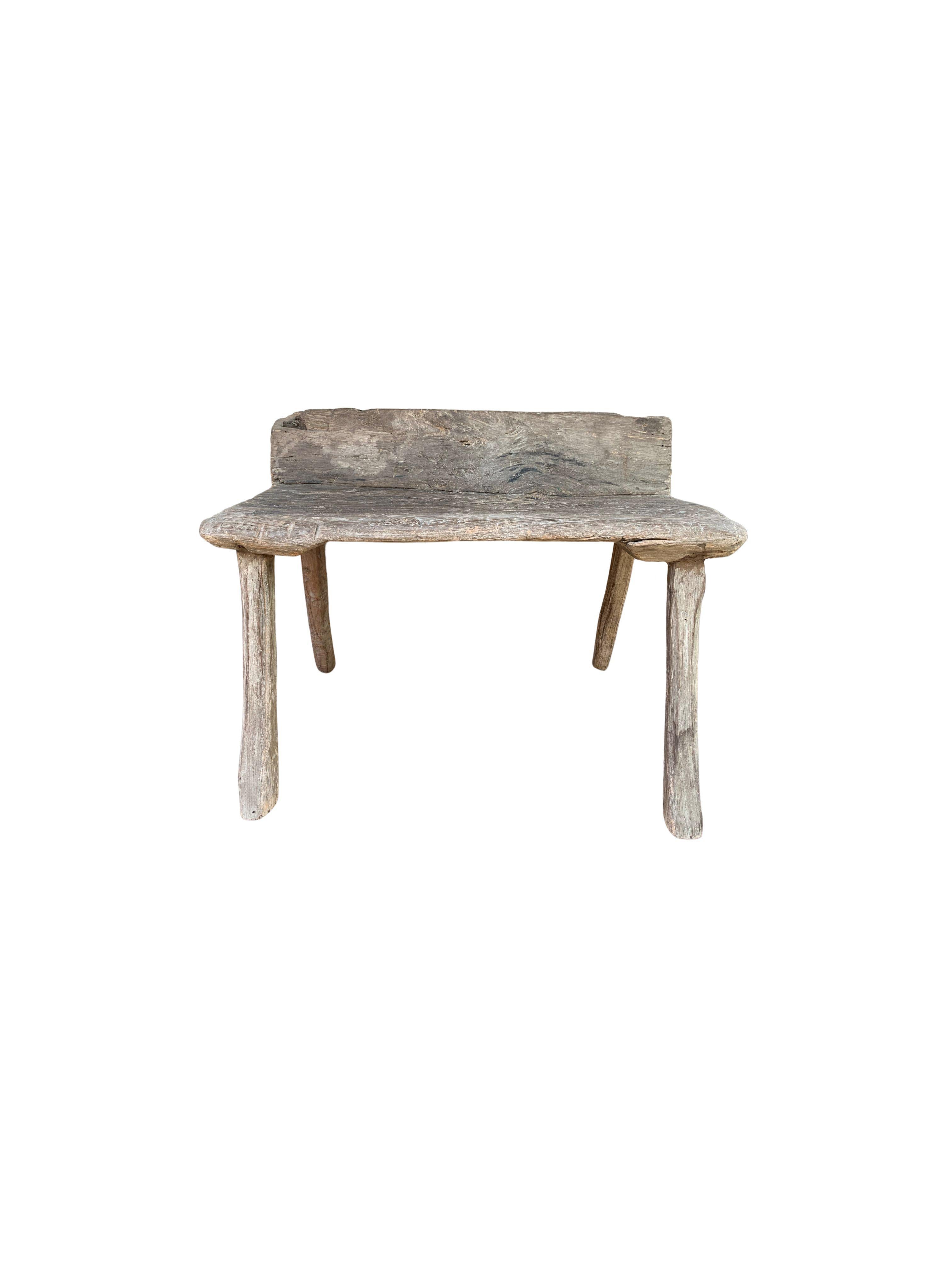 A rustic teak wood stool from the Island of Madura off the Northeastern coast of Java, Indonesia. A wonderfully sculptural object with curved feet and wonderful wood textures and shades. The age-related patina that has formed over the decades adds