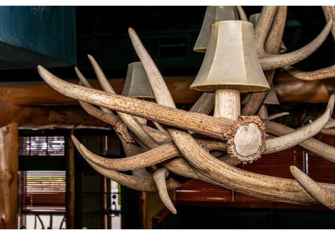 A truly Massive Lodge type Antler Chandelier with fine form and holding nine Chandelier type bulbs. The lower tier with five bulbs and the upper tier with four. There are seven original oilskin shades with some burn marks which will need to be