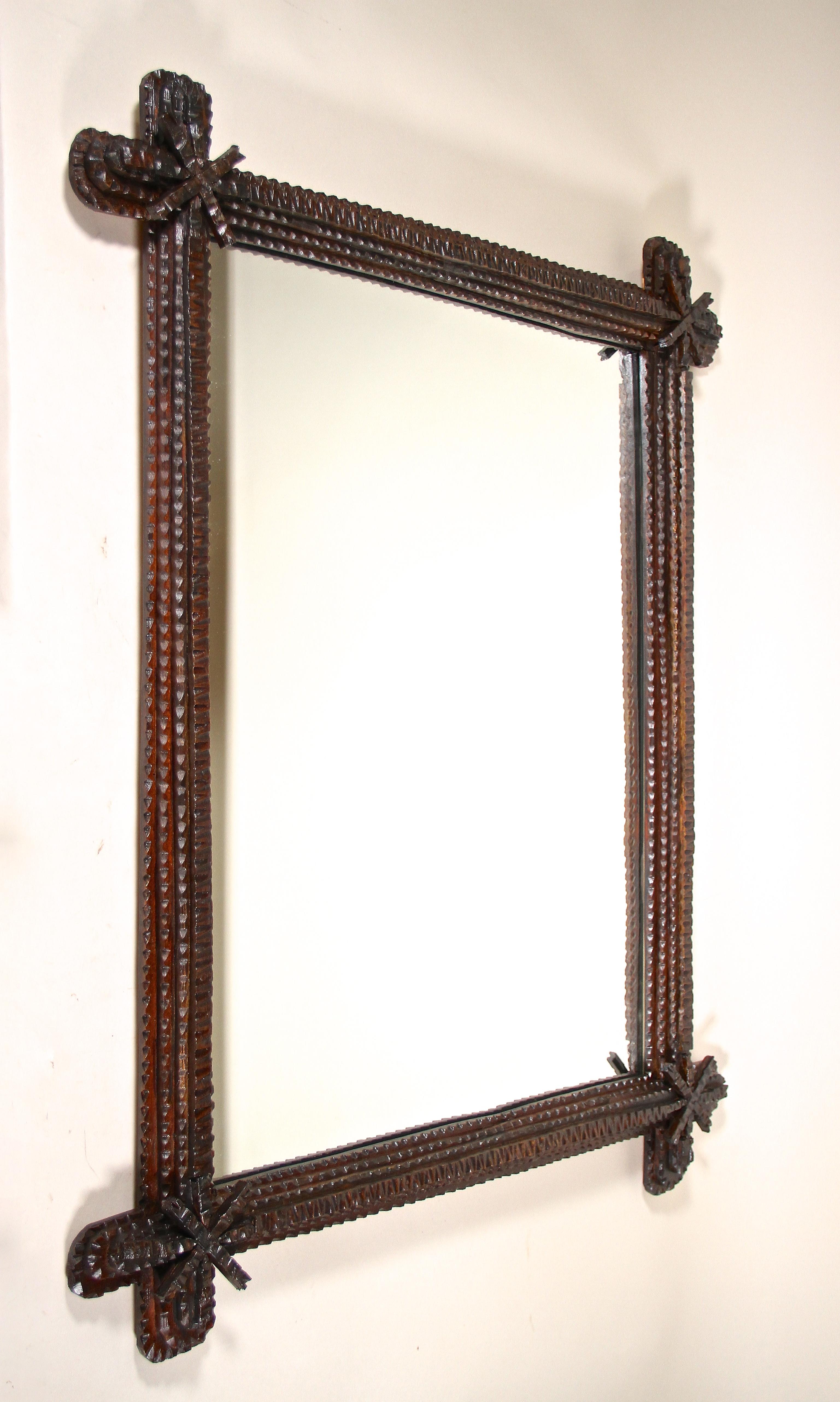 Magnificent old Rustic Tramp Art mirror from the late 19th century in Austria. Hand carved around 1870 out of basswood in a very artful way, this unique rustic wall mirror impresses with its beautiful chip carved design. The protruding, rounded