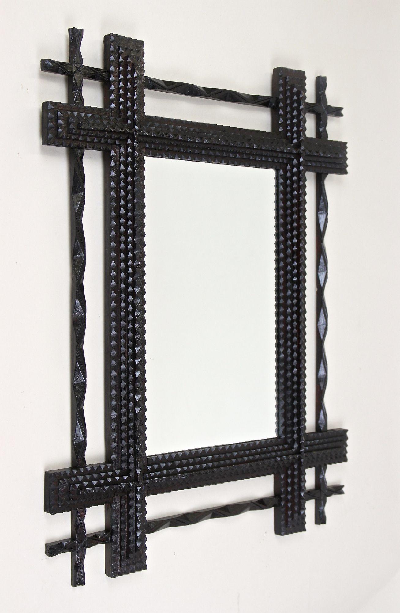 Exceptional Tramp Art wall mirror from the late 19th centuryin Austria. This lovely rustic wall mirror from the period around 1890 convinces with its great design concept: the dark stained doubled frame impresses with an unique carved narrower outer