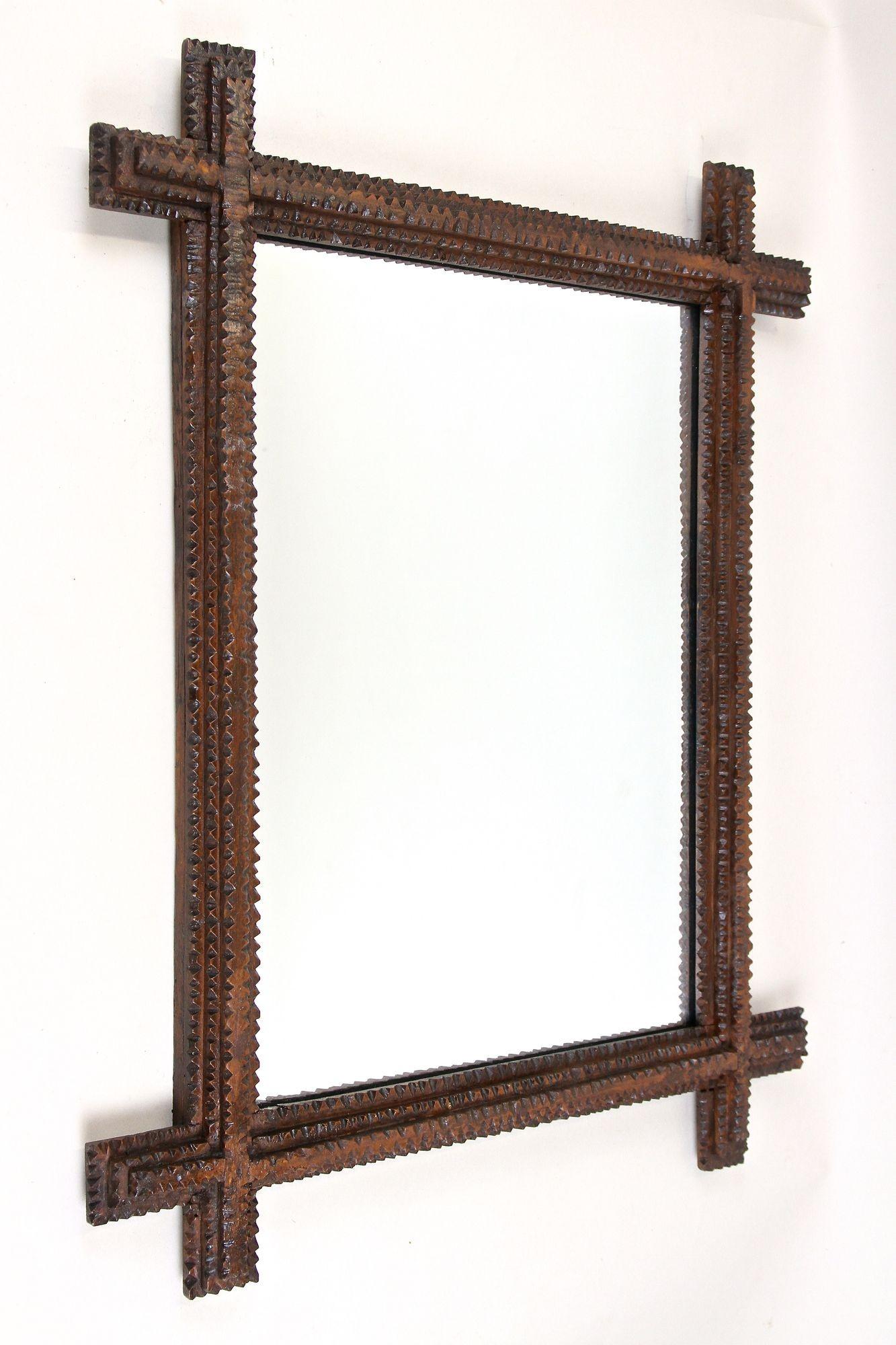 Lovely rustic Tramp Art mirror from the 19th century in Austria. This unique rural wall mirror from around 1860 convinces by its great looking, unusual handcrafted design. The extraordinary chip carved frame confers this older example of a Tramp Art