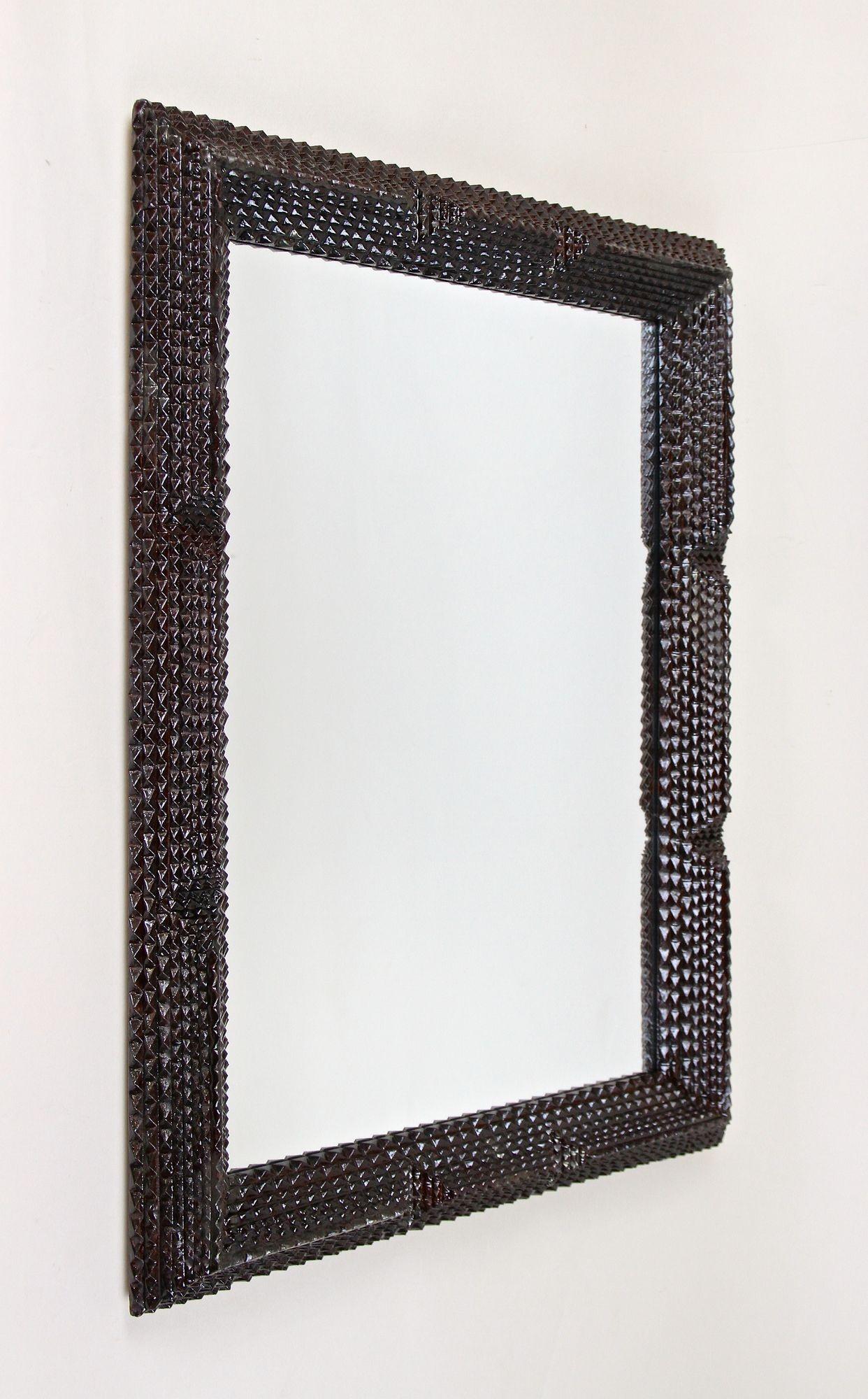 Outstanding hand carved rustic Tramp Art wall mirror from the late 19th century period in Austria. Elaborately crafted out of fine basswood around 1880, the extra broad frame impresses with its artfully pyramid notch cut design, additionally adorned