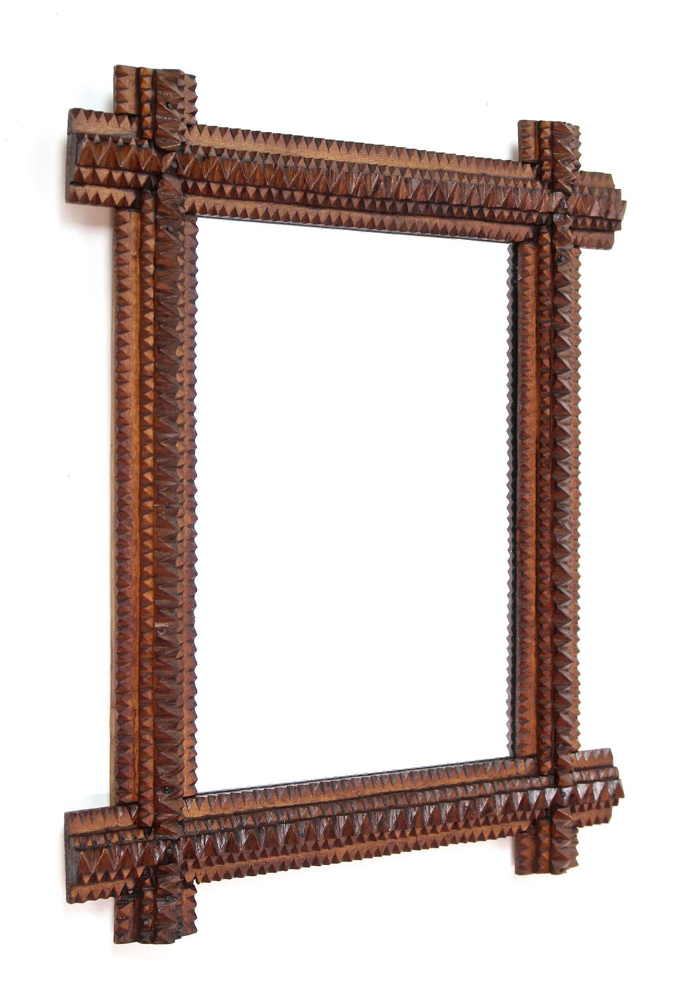 Extraordinary rustic Tramp Art mirror from the period around 1880 in Austria. Elabortely hand-carved out of basswood, this lovely small wall mirror convinces with its great looking variety of different carving techniques. Slightly protruding corners