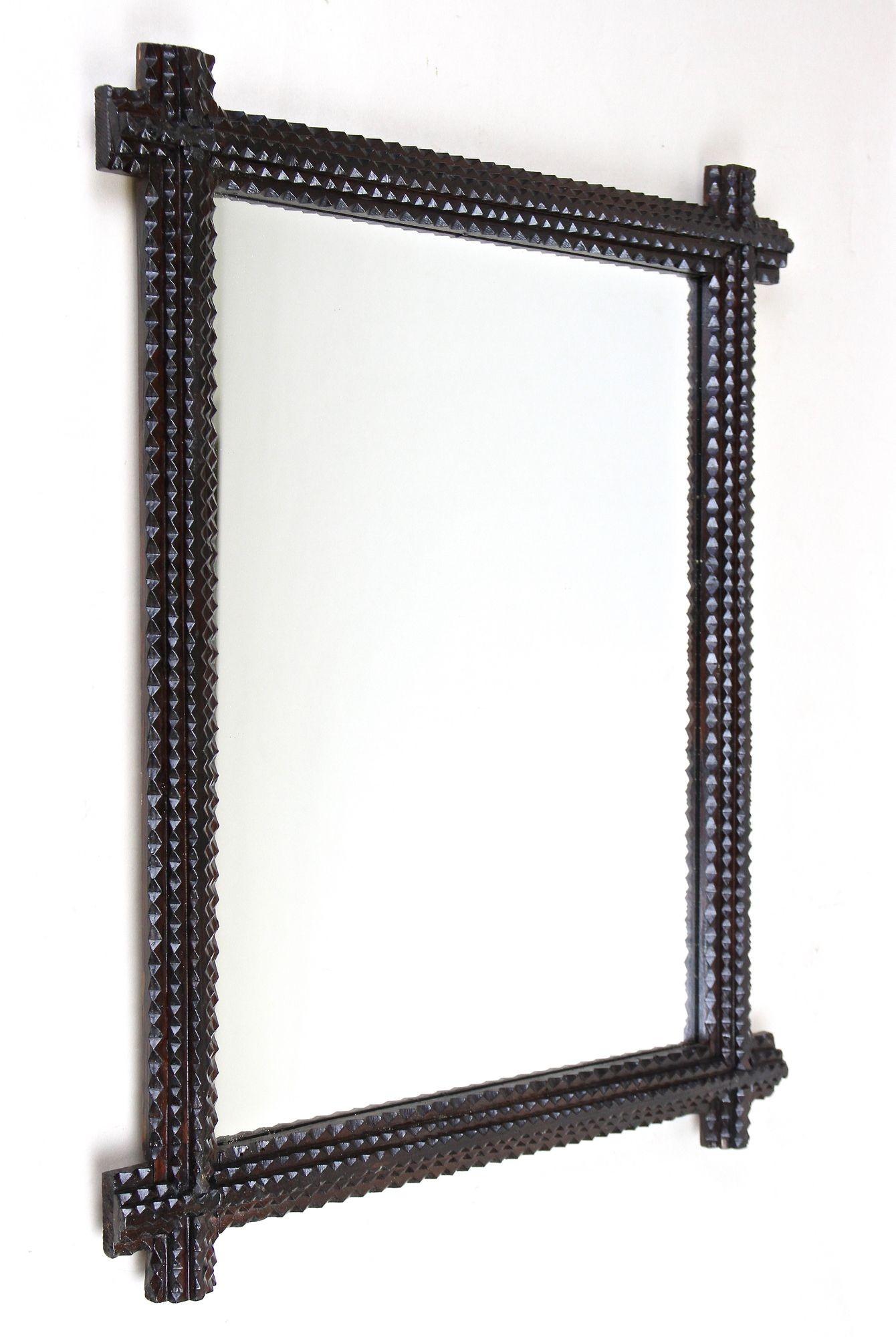 Lovely rustic Tramp Art wall mirror from the late 19th century in Austria around 1880. Elaborately hand carved out of basswood this over 140 year old Tramp Art mirror comes with a very dark brown, almost black looking surface sealed with a nice semi