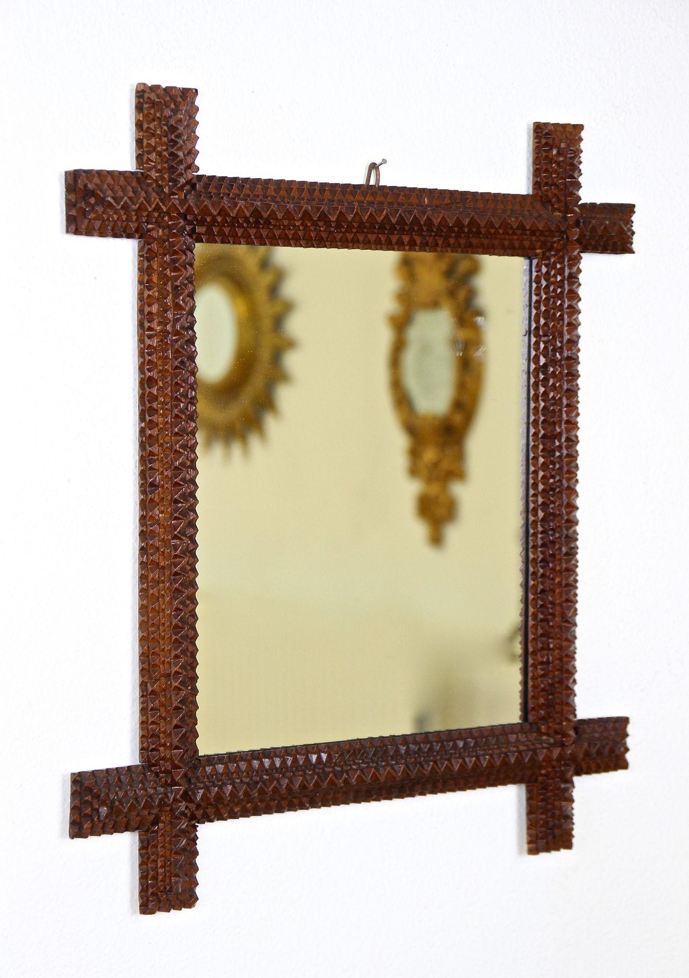 Charming rustic Tramp Art wall mirror from the period around 1880 in Austria. This unique carved wooden mirror has been artfully handcrafted in the late 19th century out of basswood and shows a lovely brown surface finished with a satin gloss
