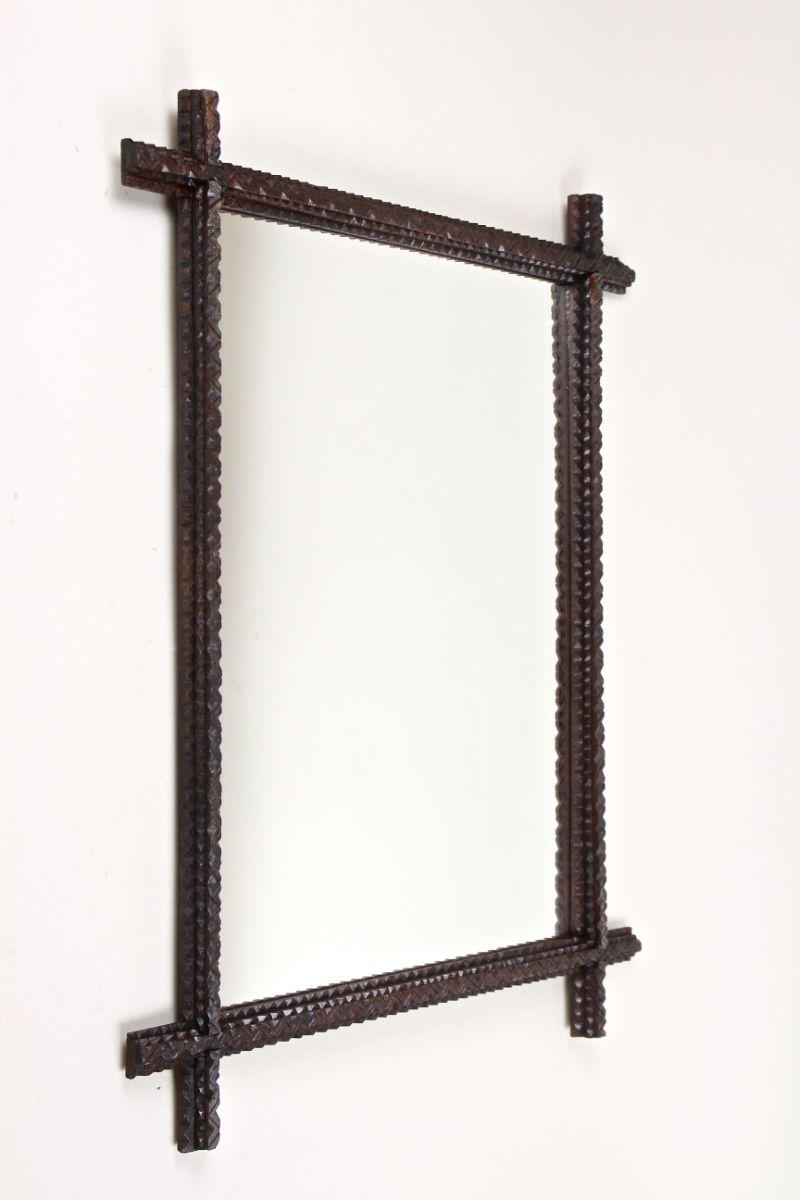 Lovely rustic tramp Art wall mirror from the period around 1870 in Austria. A great looking wooden mirror, hand made out of fine basswood showing elaborate made so-called chip carvings. The unusual hand carved frame has been stained in a wonderful