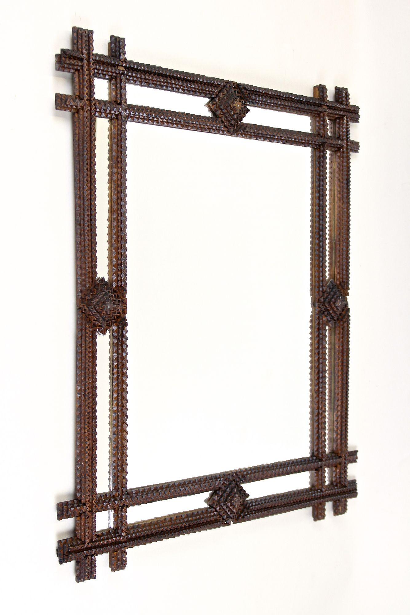 Striking Tramp Art mirror from the period around 1880 in Austria. This remarkable rustic wall mirror impresses with an artfully, absolutely elaborate handcarved design: the doubled frame with slightlyprotruding corners shows very delicate 