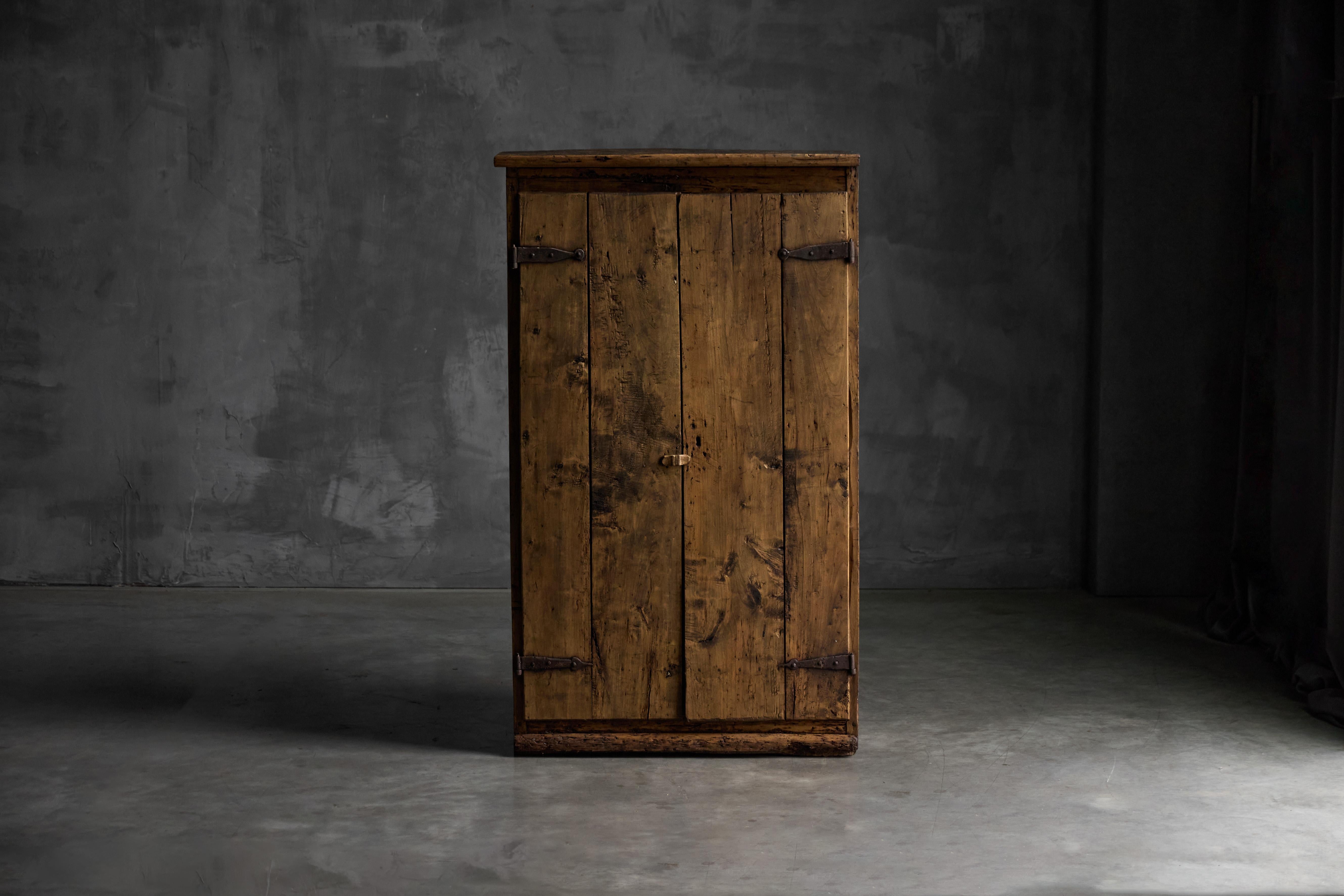 This charming French rustic cabinet, dating from the late 18th to early 19th century, is crafted from solid wood with a naturally aged surface and deep patina. The two-door façade, built from wide planks, features simple hand-forged iron hinges and