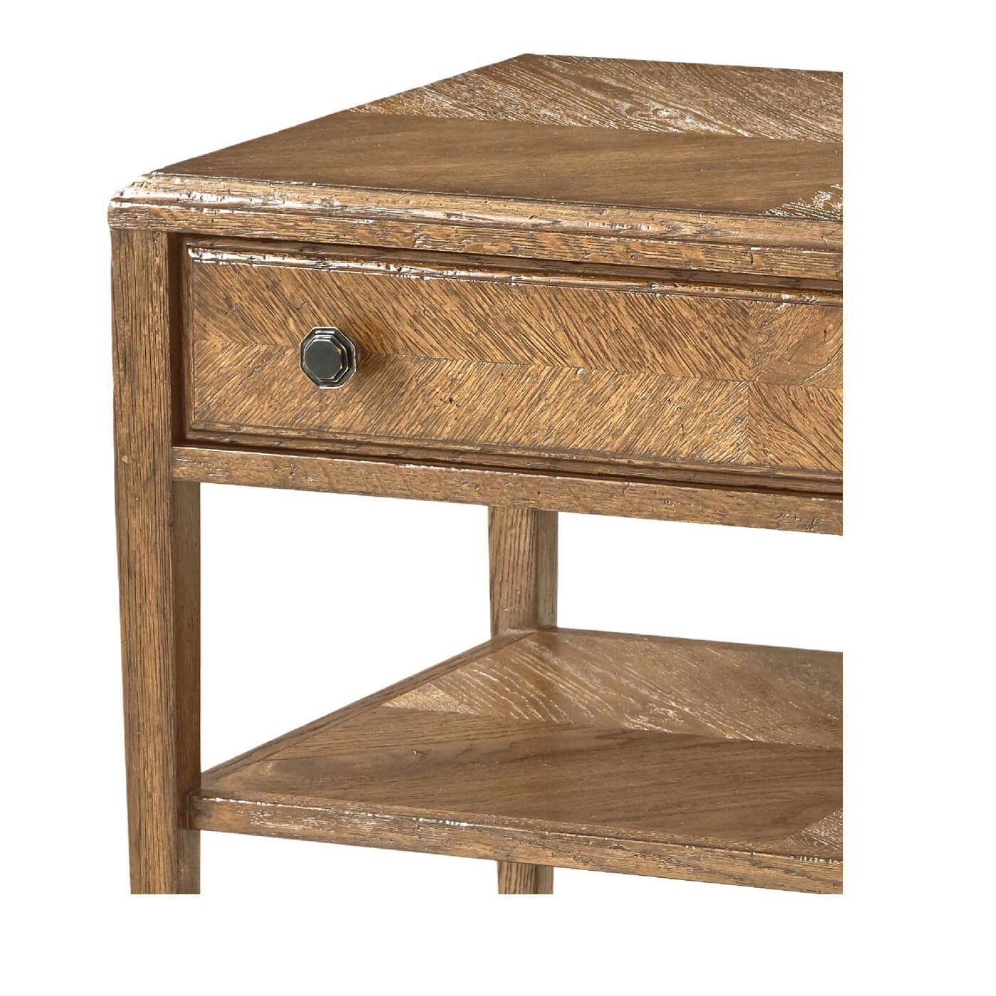 A Rustic oak two-tier nightstand with a light oak parquetry top that is mirrored on the two shelves below. It has one frieze drawer with a mirrored herringbone pattern and fine Verde Bronze handles.

Dimensions: 29