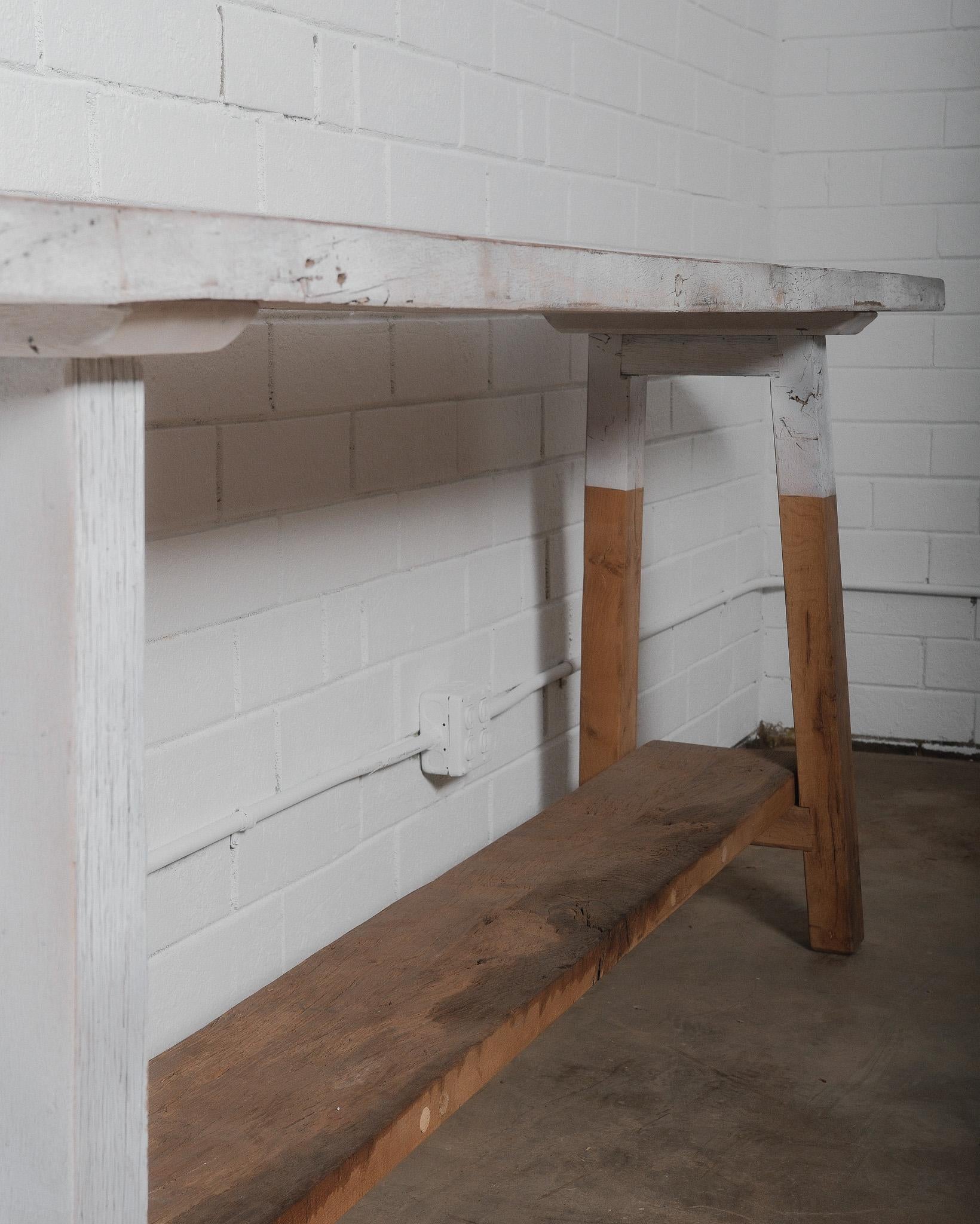 This beautifully aged rustic vintage console table showcases a distressed whitewashed finish, adding character and charm to any space. The weathered wooden tabletop features a naturally worn patina with visible grain patterns, cracks, and