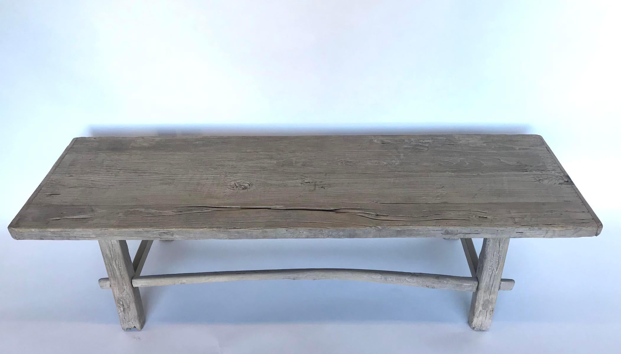 Vintage rustic Chinese Elm bench with one curved and one straight stretcher. Mortise and tenon construction. Wood is weathered with a grayish beige color, see close ups. Could work as a bench or as a skinny coffee table.
