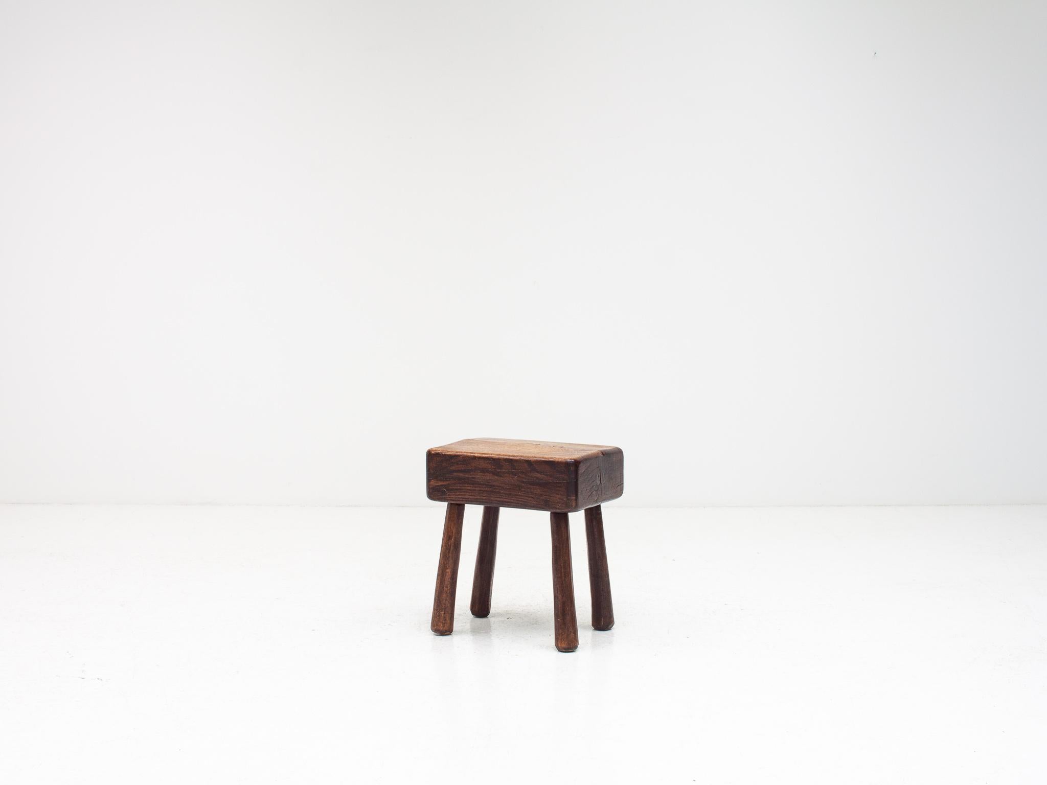 A rustic, vintage stool with a modernist feel.  Sitting on four tapered legs and formed of elm with a large slab top the piece has a great aesthetic.  Probably dating from the early 1900s.

Befitting of interiors that blend pieces of different
