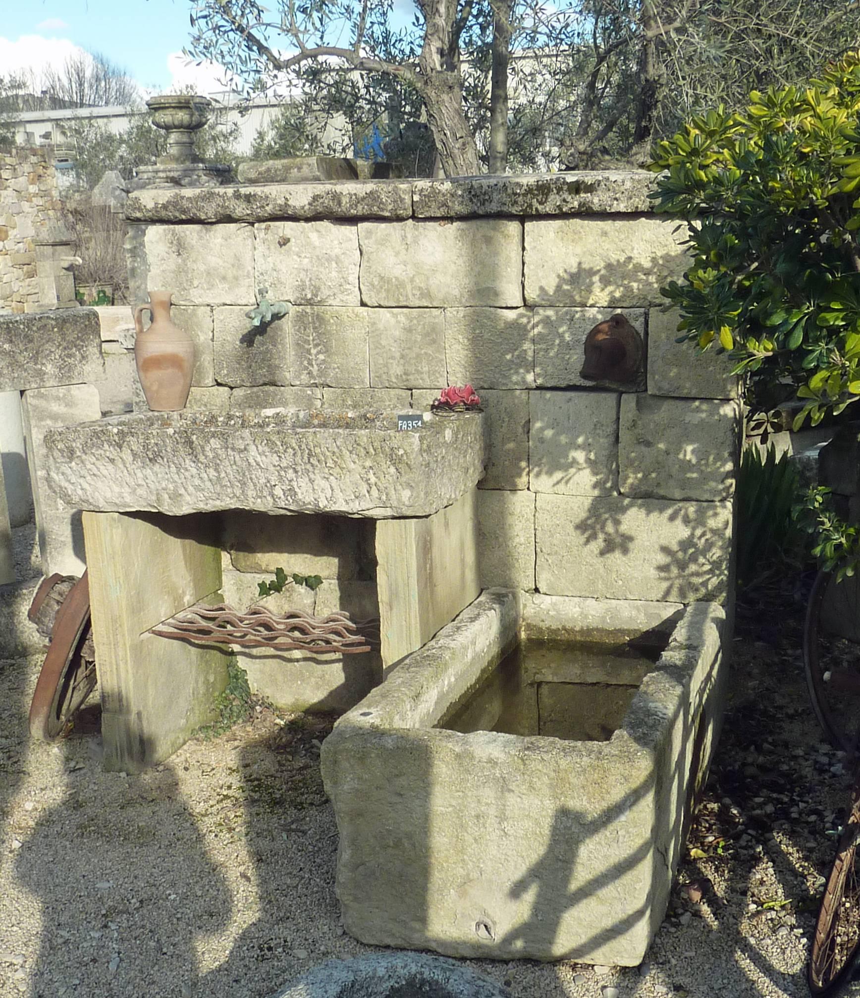 This ornamental wall fountain has been handcrafted in Provence using authentic quality reclaimed materials.

This original garden fountain has a large stone bonded wall topped by thick copings. An antique cast iron water outlet placed above a