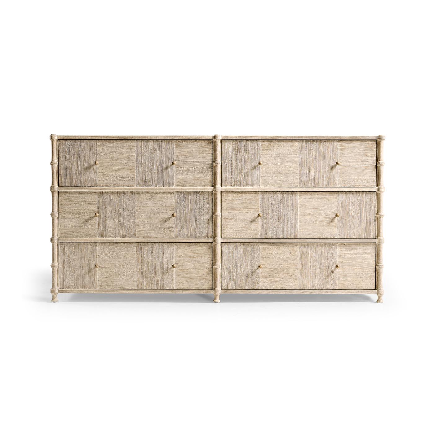 Realizzato in legno di acacia e quercia con finitura lavata per un'atmosfera rilassata e sofisticata. I frontali dei cassetti in parquet con bordi a coste aggiungono consistenza, mentre le modanature ispirate al bambù ne esaltano il fascino
