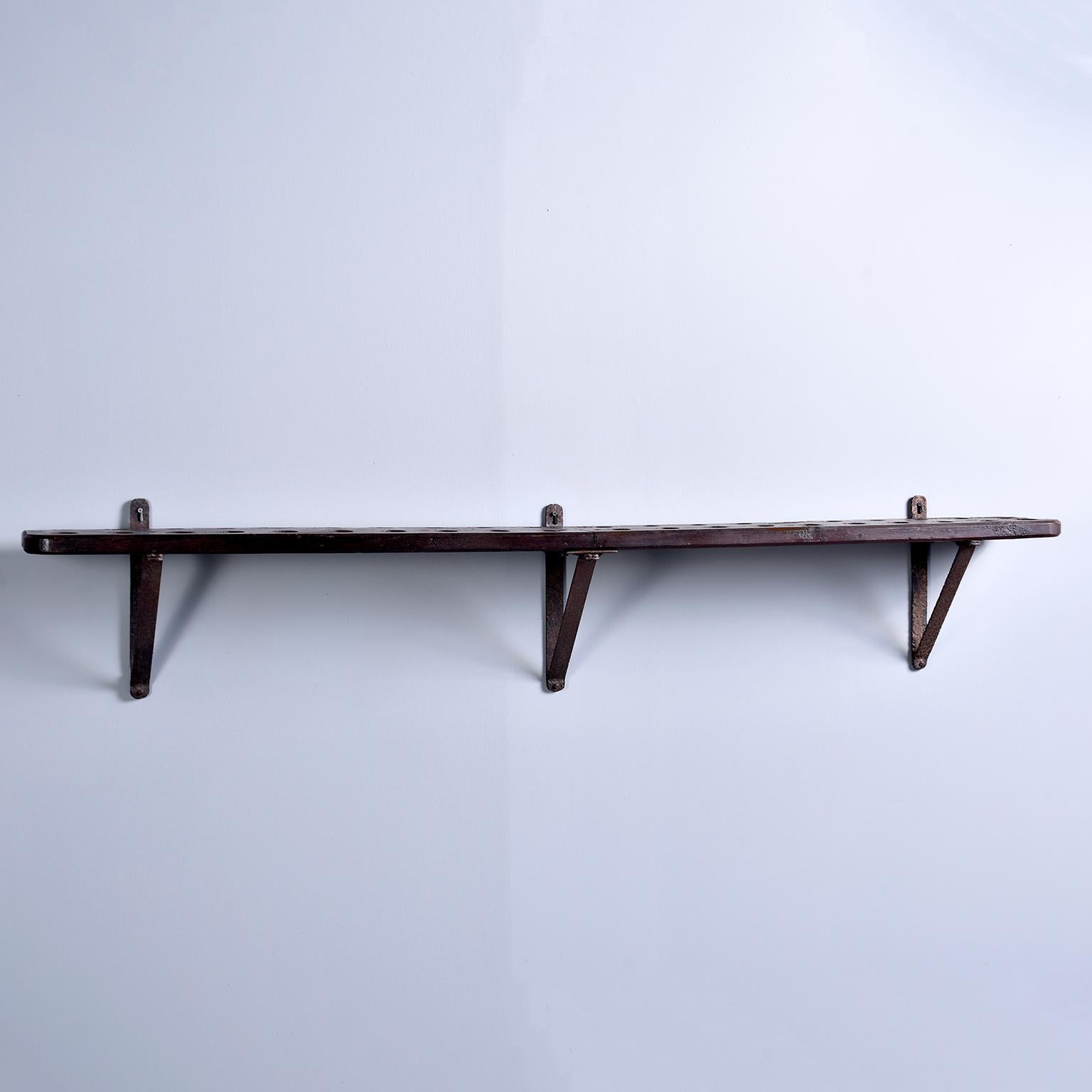 Early 20th century rustic French shelf-style wood and iron wine rack. Consists of heavy wood shelf with holes to store wine bottles upside down (keeps the cork wet) and iron supports. Great authentic piece for a home or commercial bar.