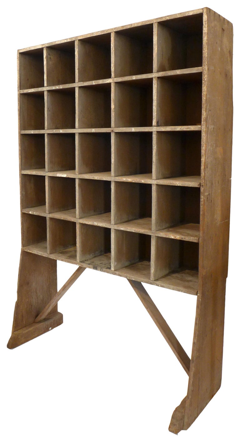 A fantastic rustic wood open-cubby storage unit.  A wonderfully weathered and alluring, monochromatic edifice, effectively if simply constructed.  A grid of deep storage cubes retaining alphabetical label remnants, held on tapering,