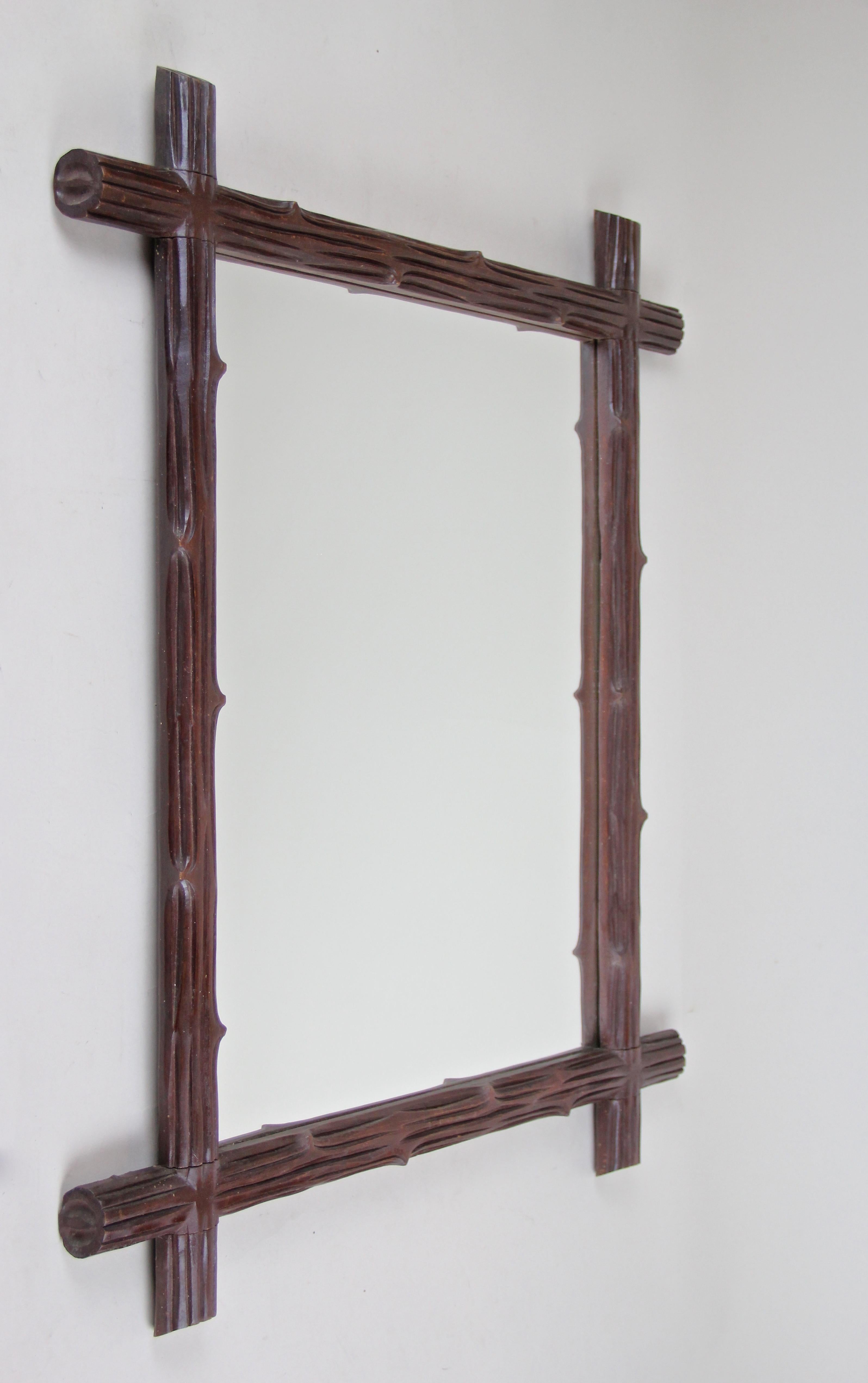 From circa 1900, the turn of the century in Austria comes this lovely wooden black forest wall mirror. A simple but elegant design was created out of hand carved basswood, showing the typical 