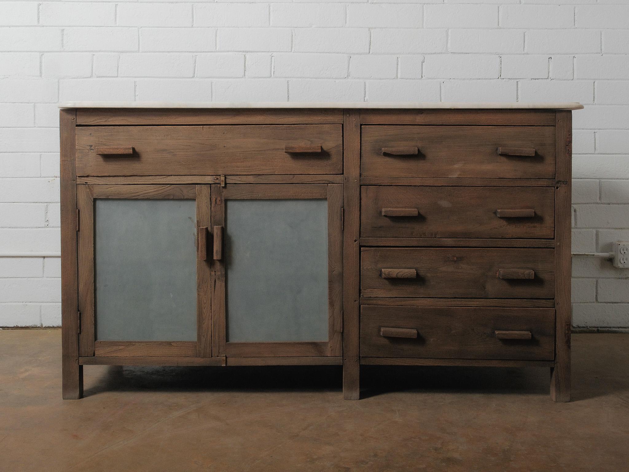 A character-rich wooden sideboard featuring a warm, weathered finish, a smooth marble top, and a balanced combination of frosted panel doors and sturdy drawers. The piece offers generous storage with five drawers and a double-door cabinet, each