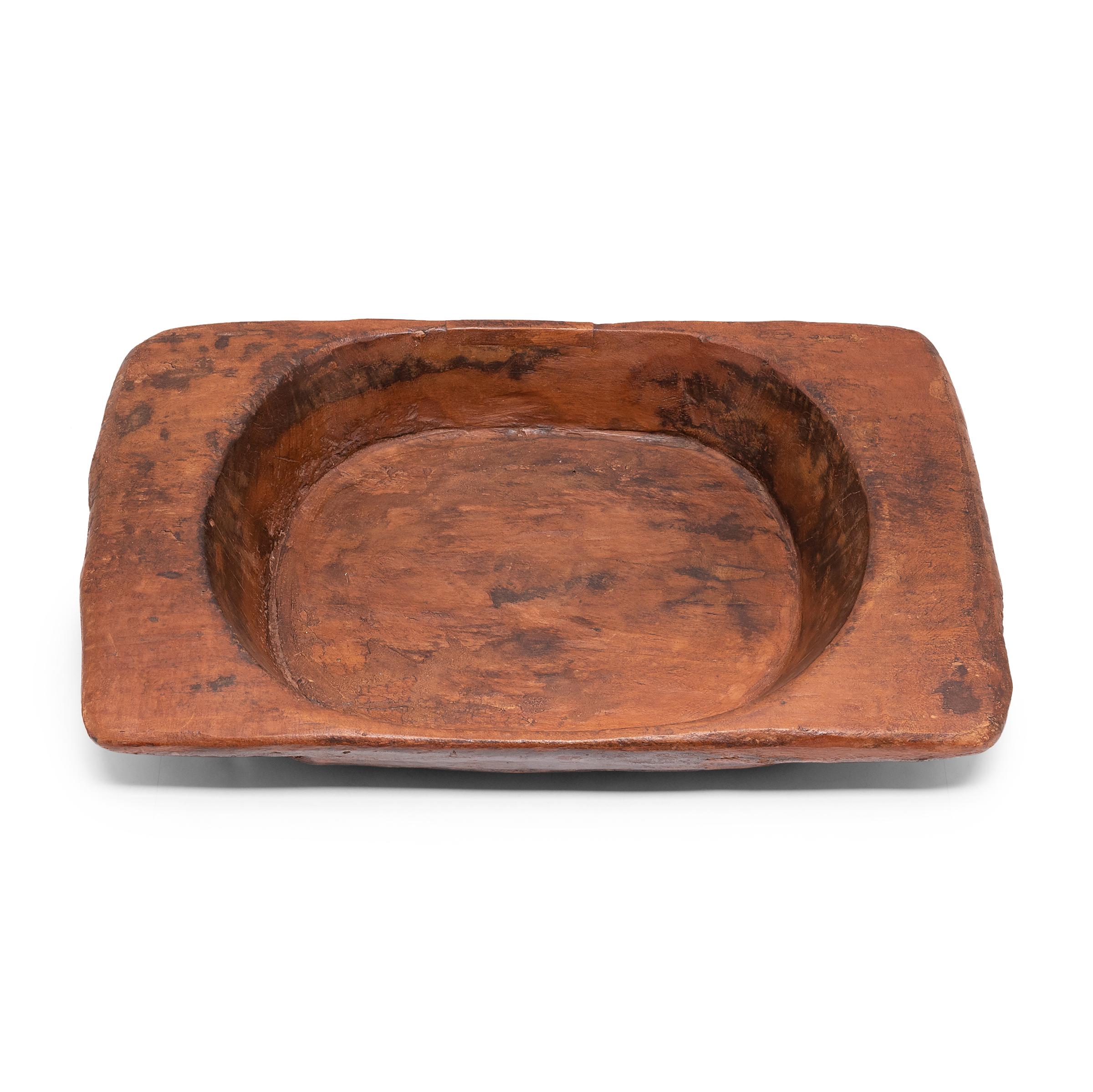 Carved from a large length of northern elmwood, this primitive tray charms with its humble rustic finish and simple form. Marked with use and traces of its original dark finish, the weathered tray calls to be touched. The time-honored tray brings