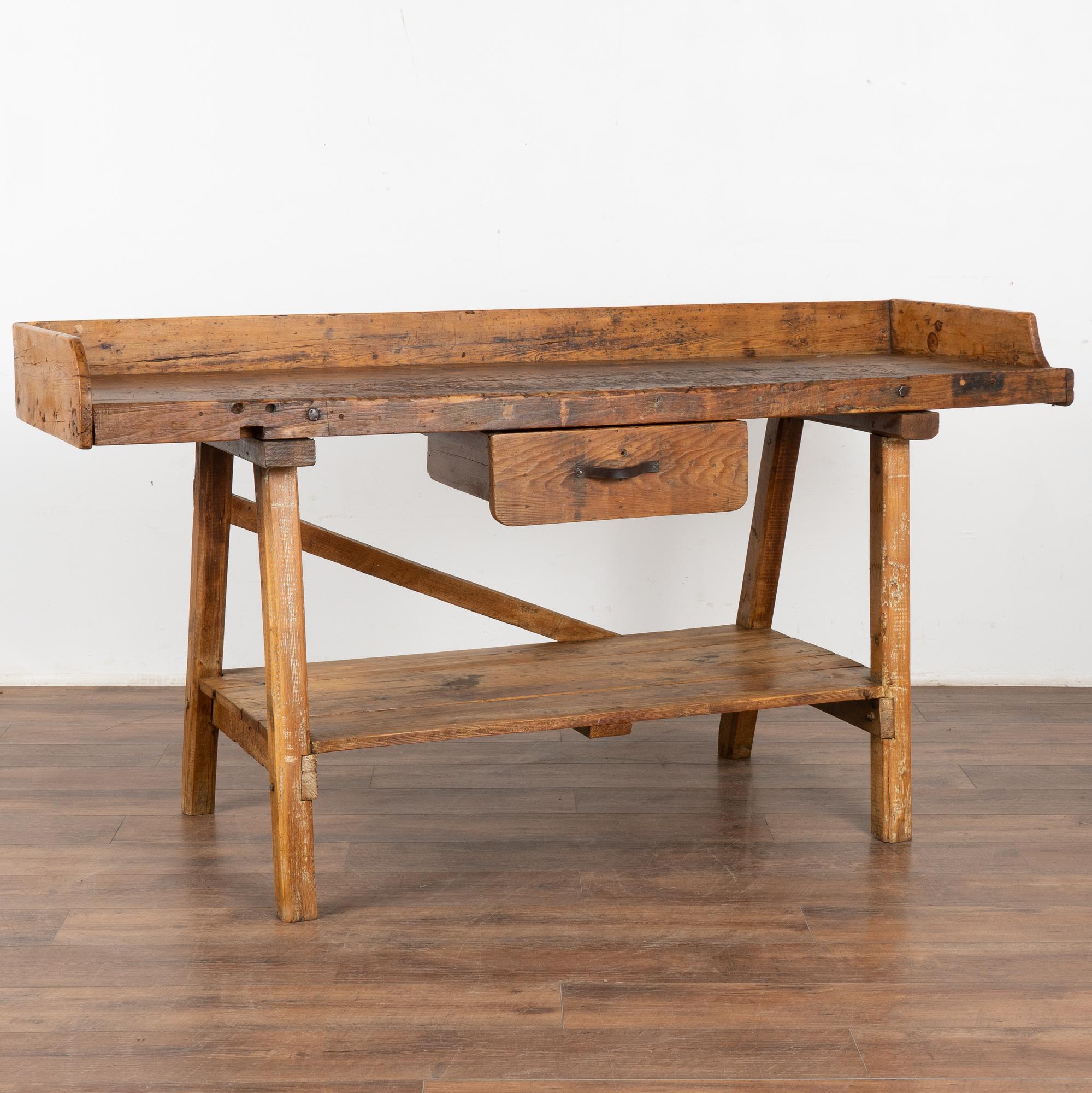 Rustic work table with single and lower shelf that can serve as a unique console table or informal bar.
This heavily used table reflects generations of use in every gouge, nick, scratch, hole and stain. Typical age related separation of planks and