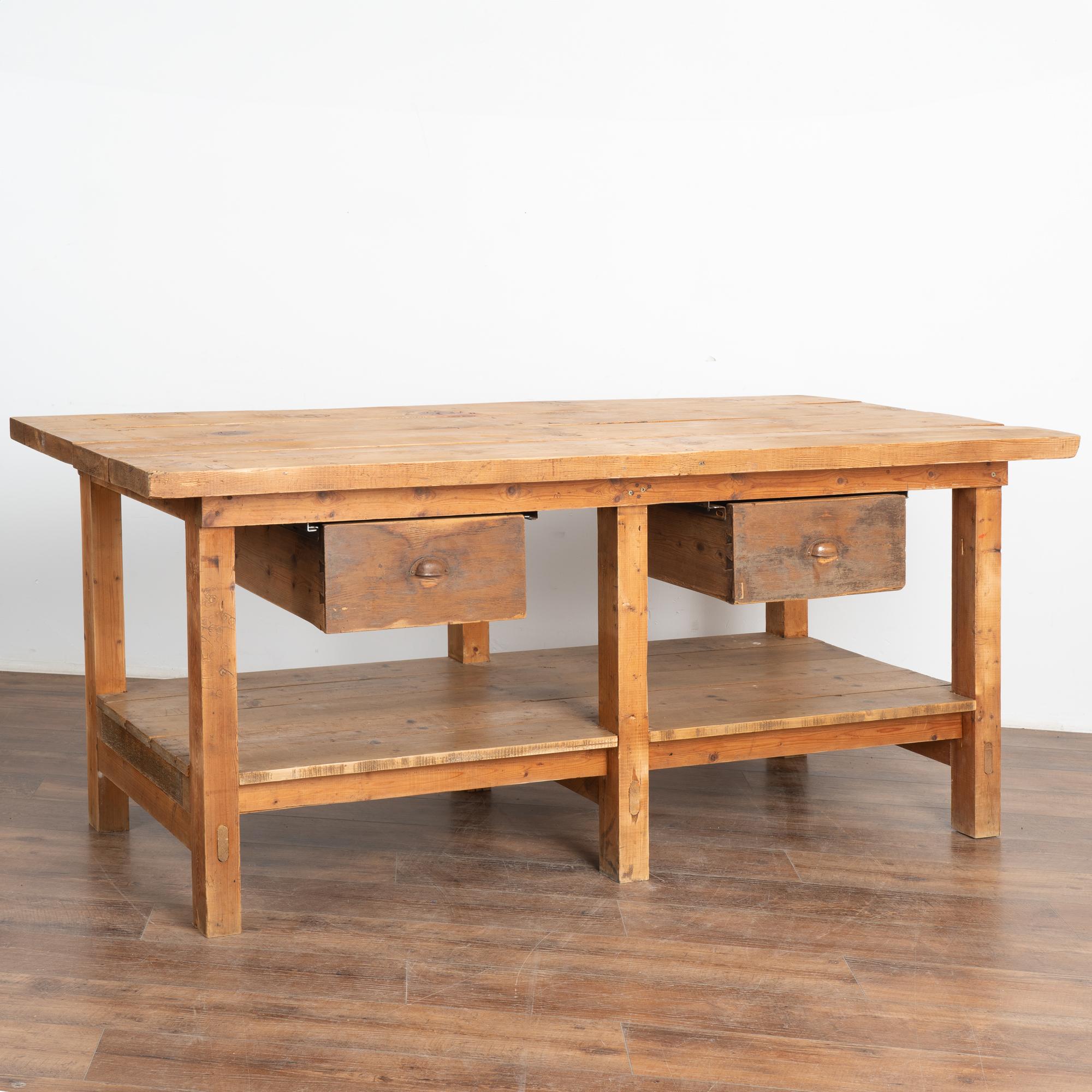 Rustic work table or shop counter with two large drawers and lower shelf. 
This heavily used table reflects generations of use in every gouge, nick, scratch, stains and minor paint. Typical aged separation of planks.
This work table is loaded with