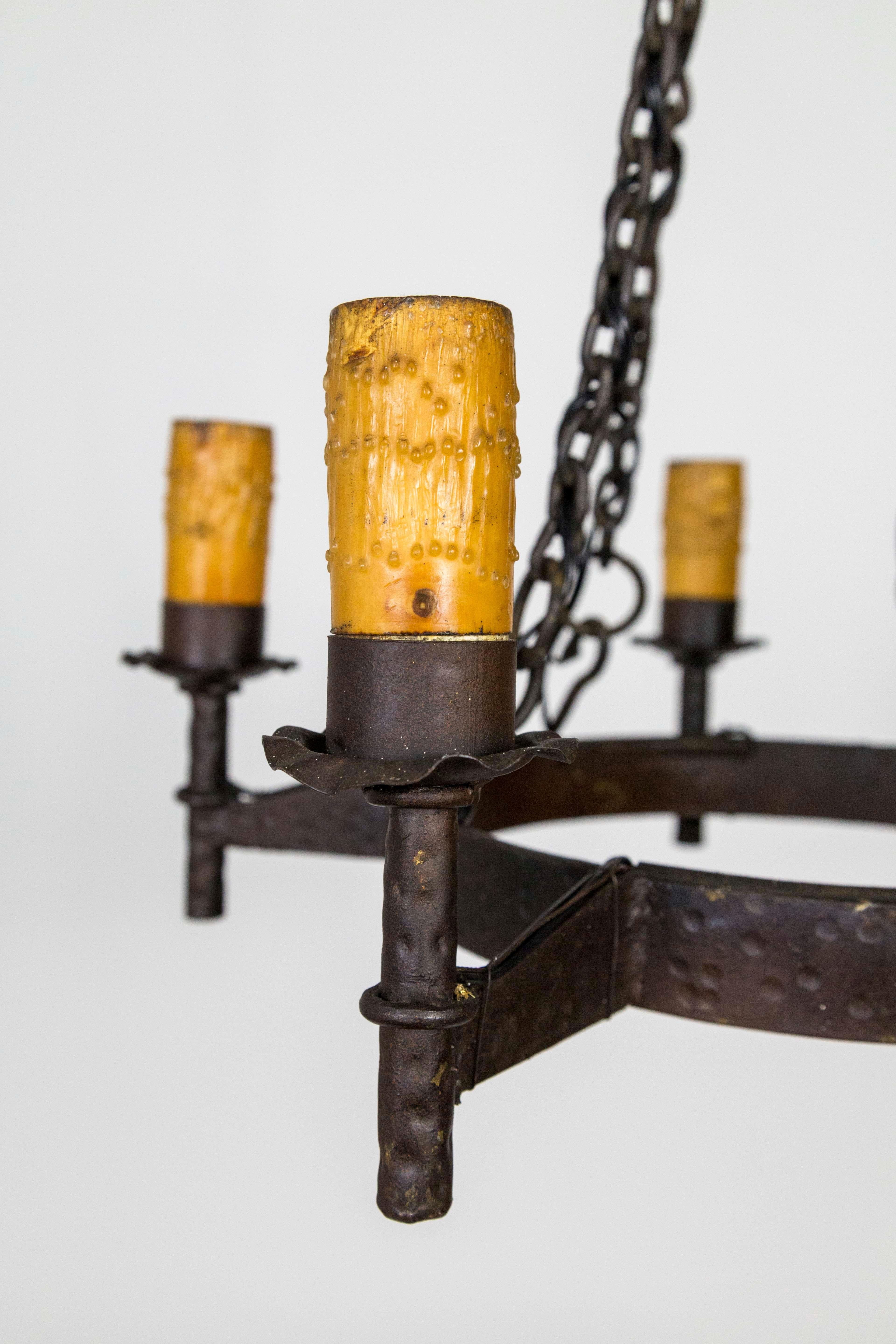 Handwrought iron, medieval Revival chandelier with hammered texture and five-light with stout, beeswax covered, wooden candle covers, American, 1910. Newly rewired. Measures: 22