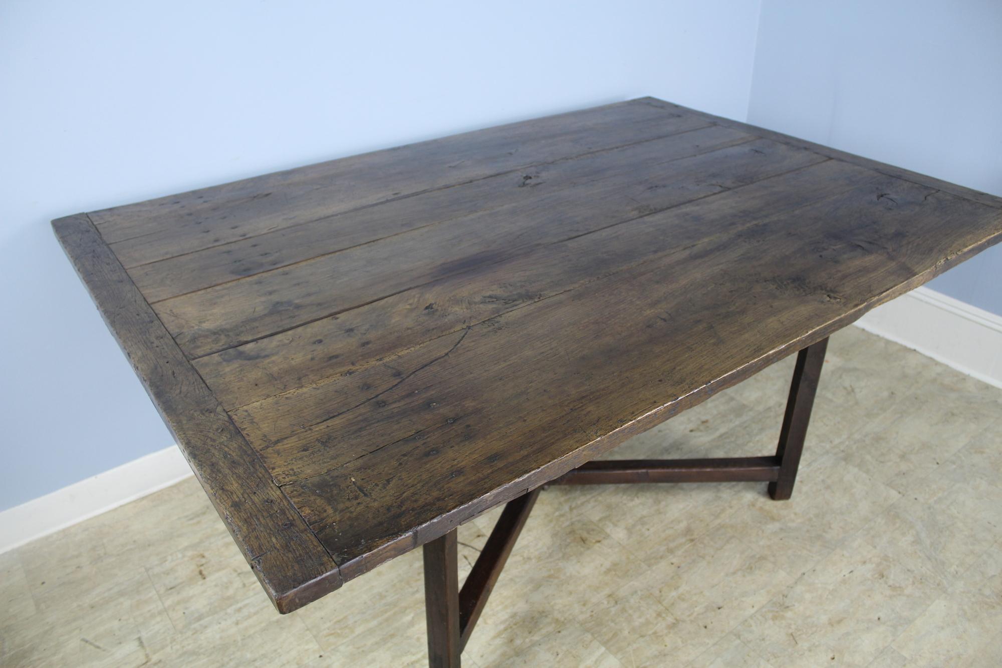 A rustic X based farm table with wonderful distressed patina and color. Bread board ends and interesting natural grain. With no legs or apron to get in the way, this table seats 8 comfortably. Formerly a folding table, the legs have been fixed into