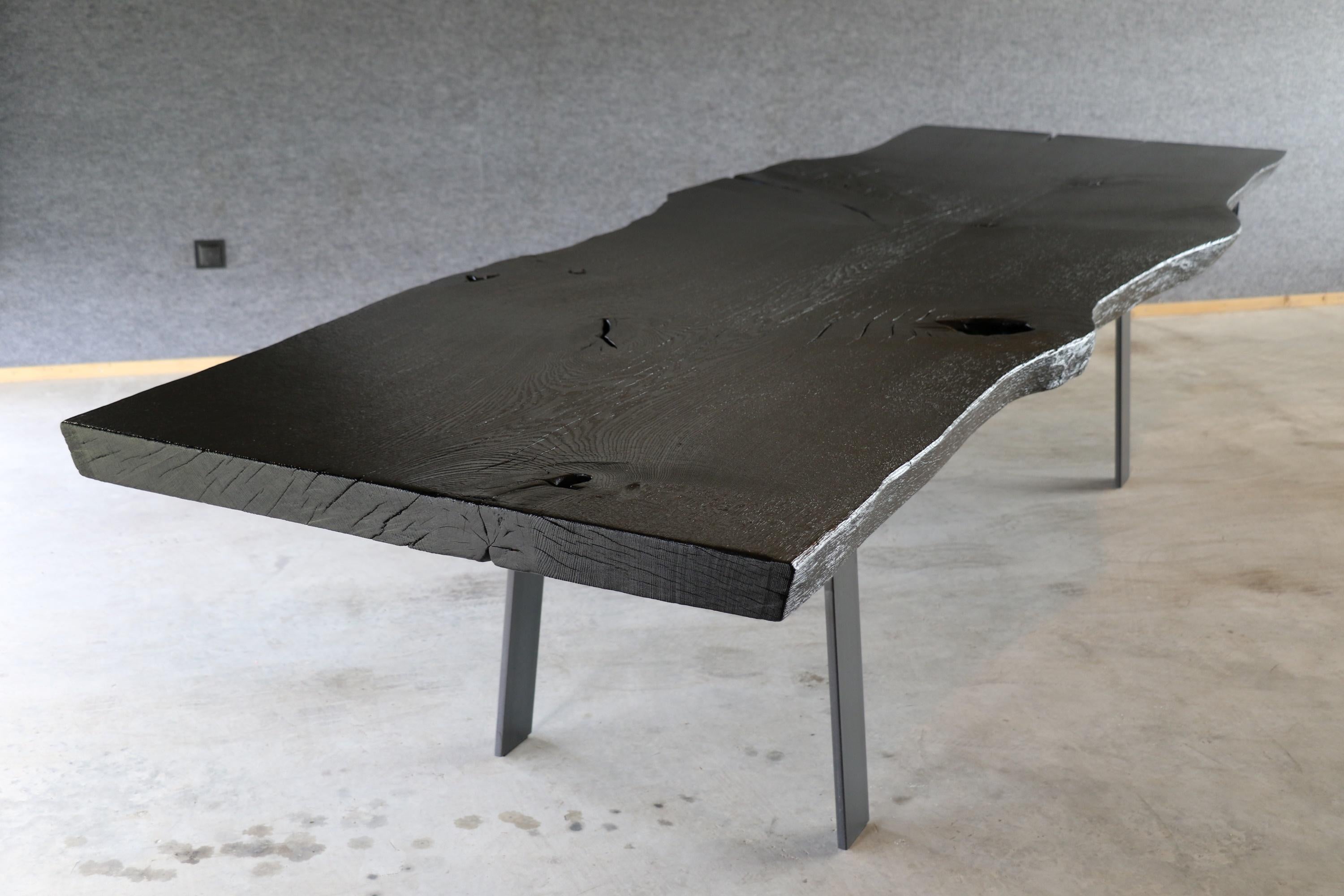 Cette table en Unikat avec un revêtement de sol léché peut être remplacée en un seul bloc par une table en bois de chêne. La combinaison d'une terre noire, façonnée par le feu selon une tradition vieille de plus d'un siècle, et d'une pierre taillée