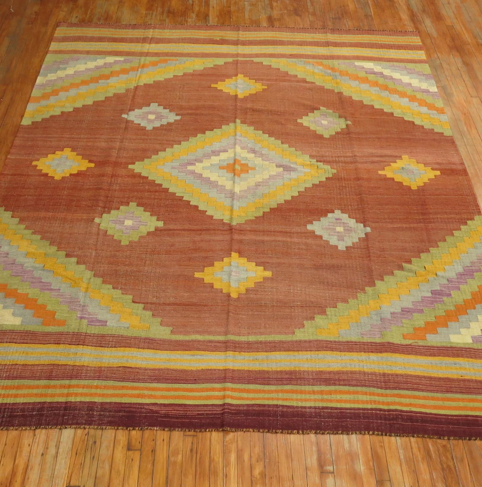 A room size mid-20th century Turkish Kilim flat-weave with pretty accents in lavender, blue-gray, yellow and soft green on a brown rust colored field.

Measures: 9'4