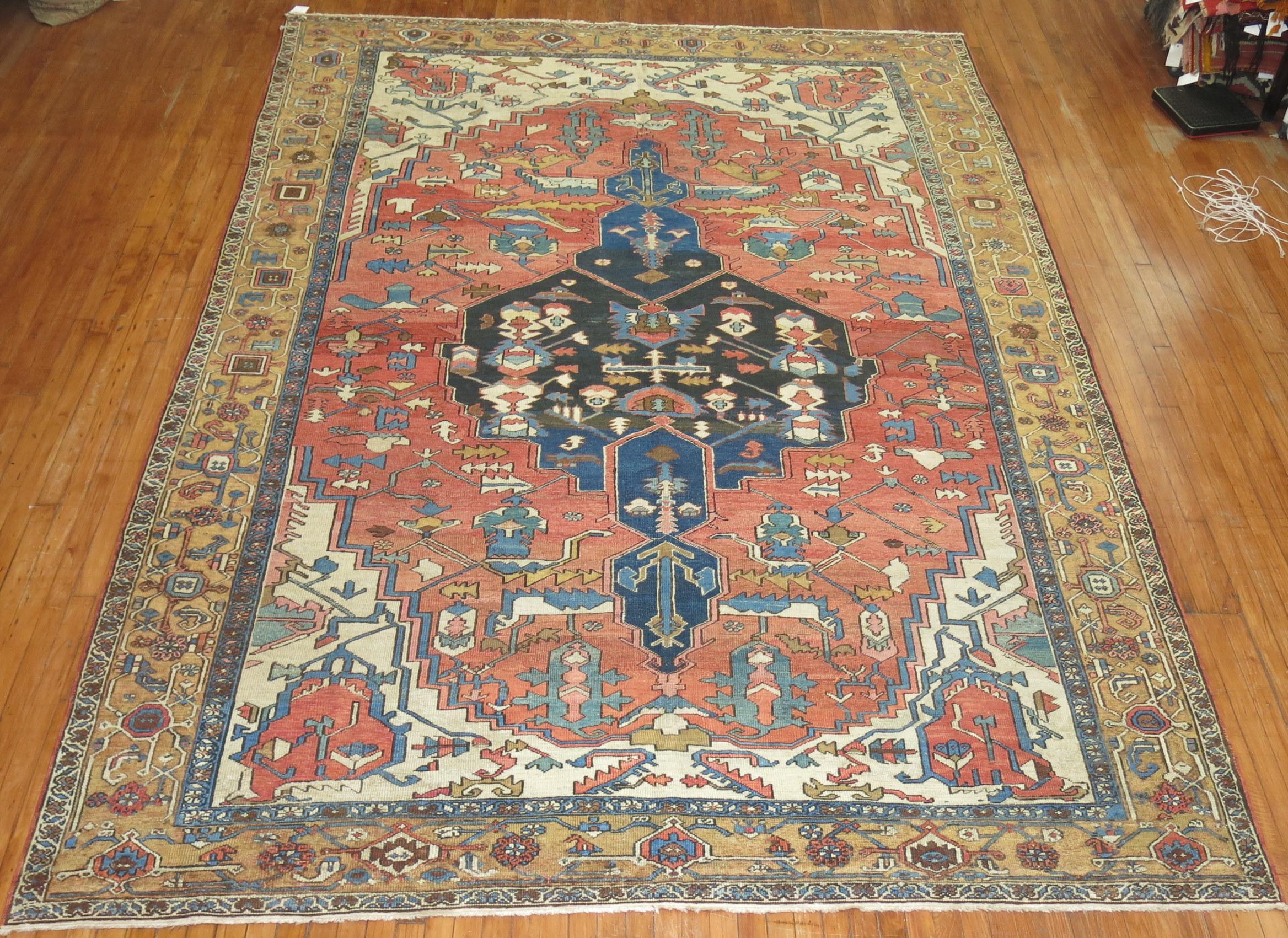 Room size Persian Heriz rug. Orangy-rust field, charcoal and blue abrashed medallion with a camel border. Traditional Medallion design. 

Measures: 8'11'' x 12'10''

Heriz carpets are beloved for their versatility. Their geometry complements