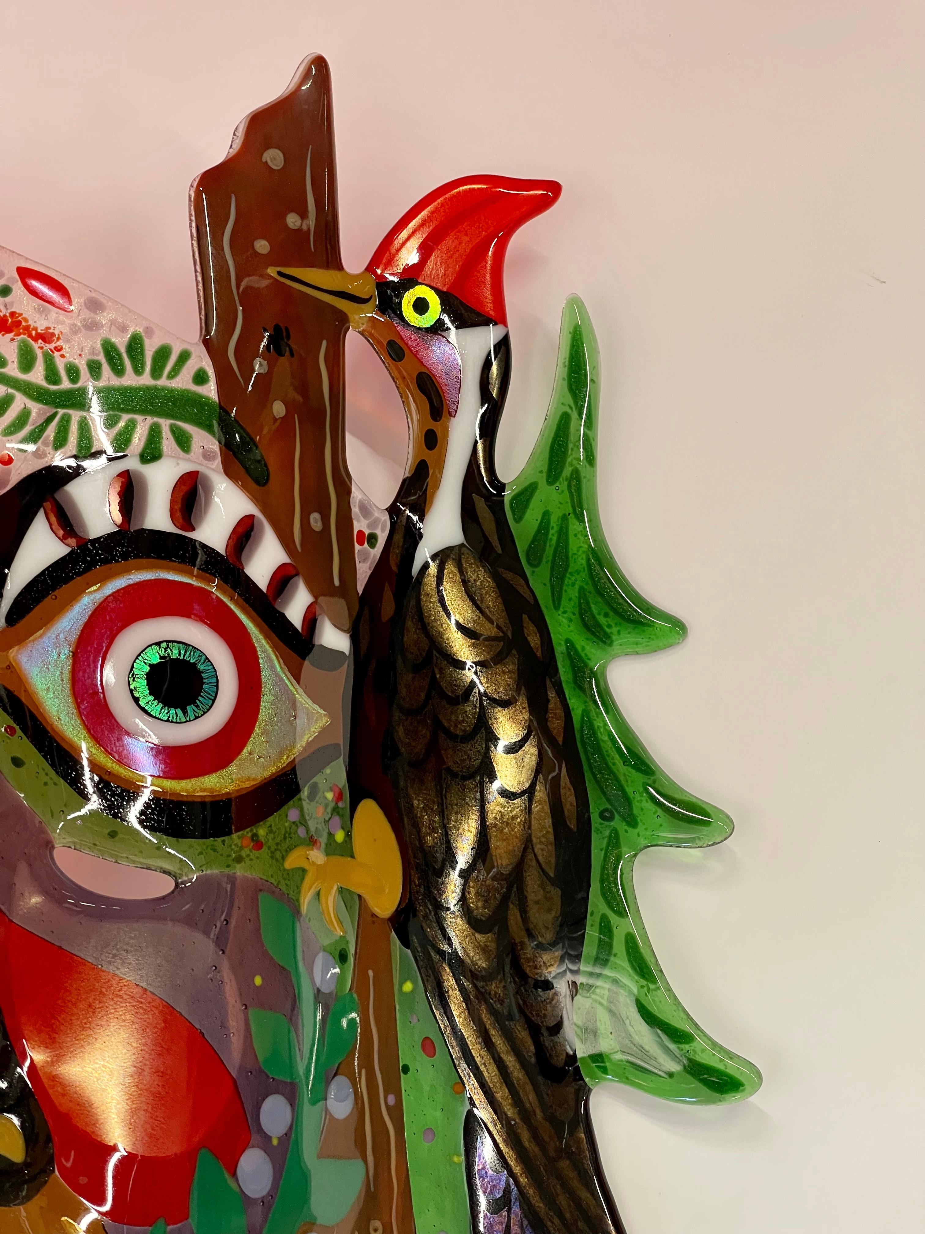 A whimsical colorful glass mask with a woodpecker by the noted glass artist Ruth Brockmann. It is signed and dated 96. In very good condition.