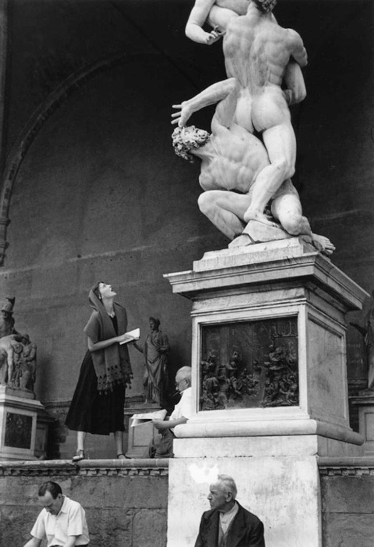 Jinx Staring, Florence by Ruth Orkin presents a woman staring up at a detailed sculpture of two men in the nude. Her facial expression reflects the sculpture's expression, creating an intense connection between her and the artwork. 

Blind stamp on