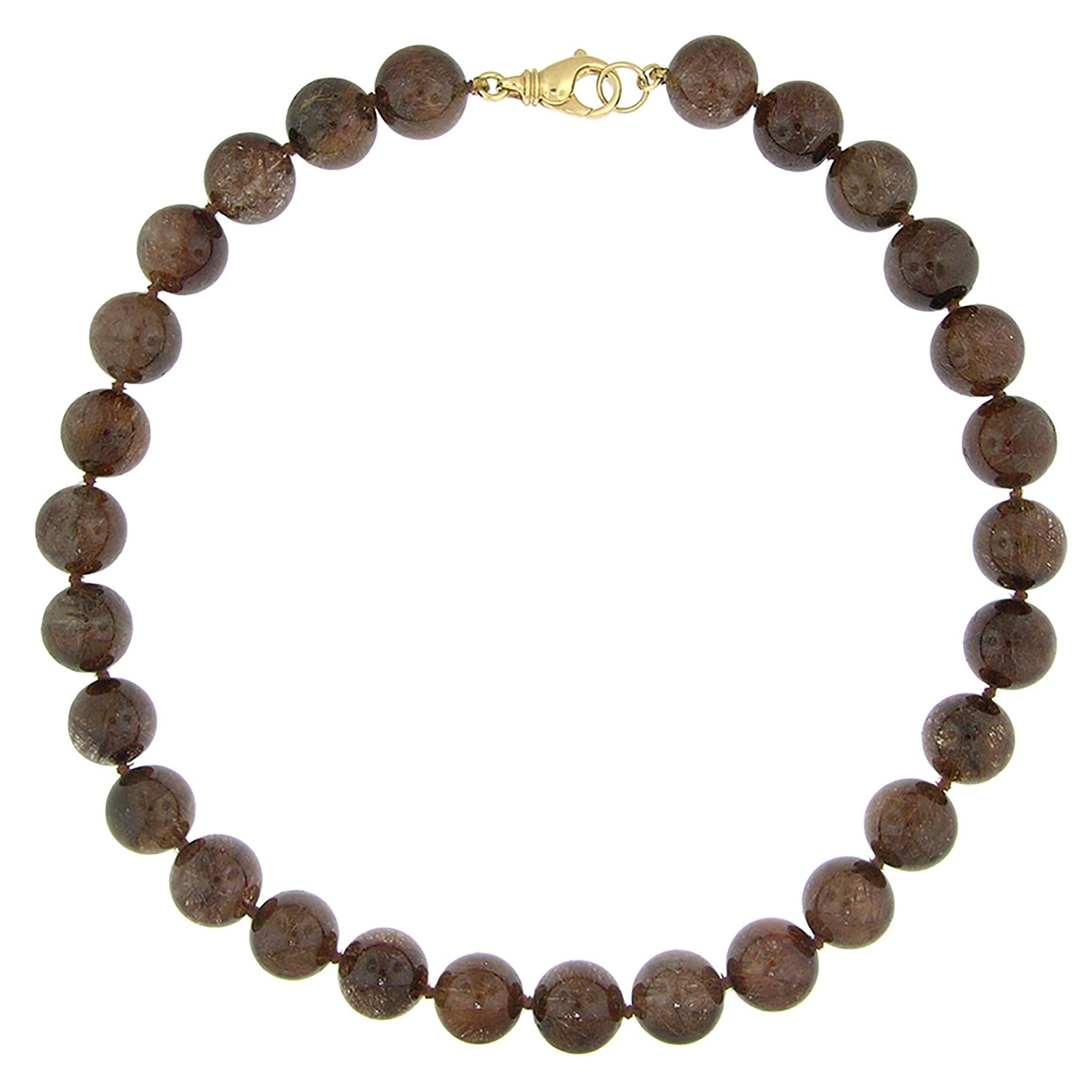 This gemstone beaded necklace showcases a luxurious rutillated quartz. This is a clear, colorless quartz with an extremely dense population of golden rutile needles. The richness of the look will elevate any outift.

This necklace is finished with