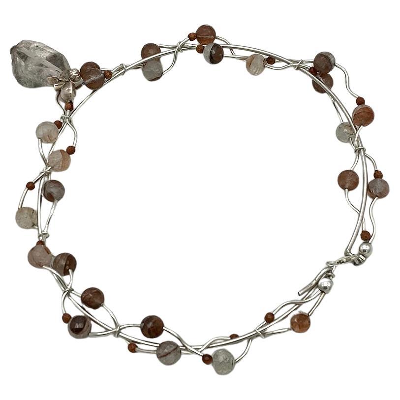 This is a rutilated quartz and sterling necklace with pendant. We created it with 8-9 mm faceted copper translucent rutilated quartz balls and sterling curved tubes. It has a 1 x 1.38 x 0.63 inch freeform nugget quartz pendant with inclusions as