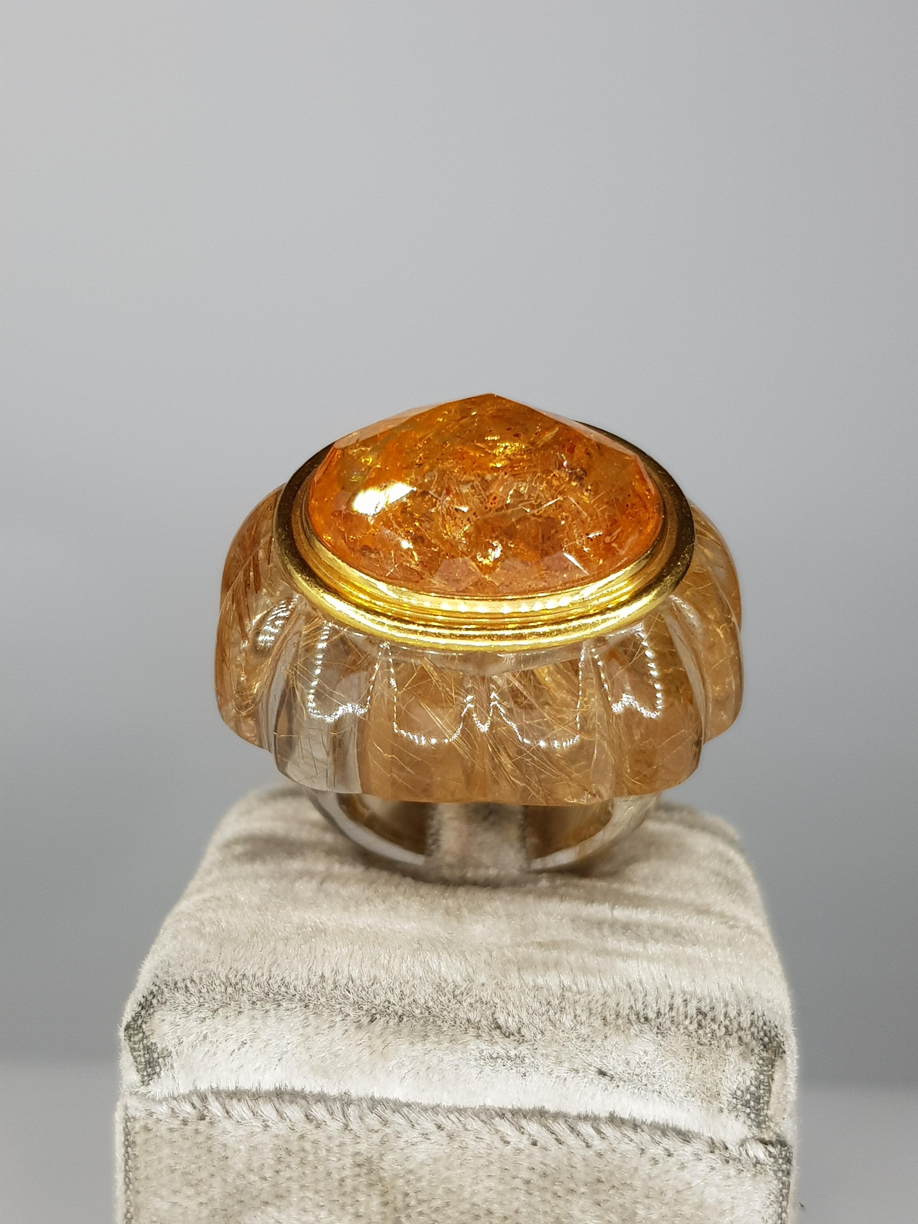 A Ring engraved in Rutilated Quartz, with an oval central Imperial Topaz, briolé cut, embedded in yellow 18 kt gold. 
Very luminous and elegant, this unique piece has an extremely fine, handmade craftmanship 