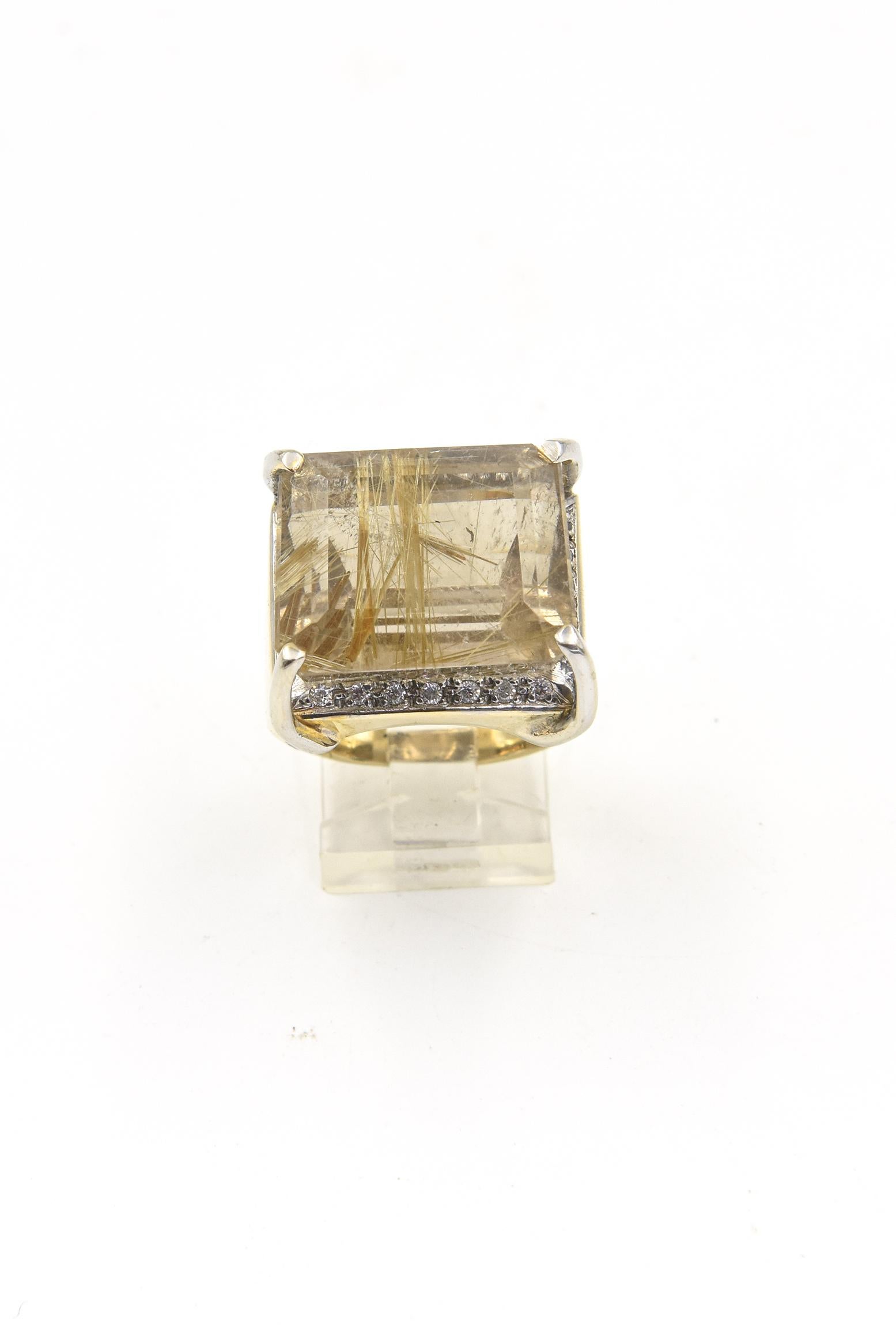 Stunning faceted rectangular rutilated quartz mounted in a wide 14k yellow gold band with cubic zirconia accents forming a frame.  The ring is .85