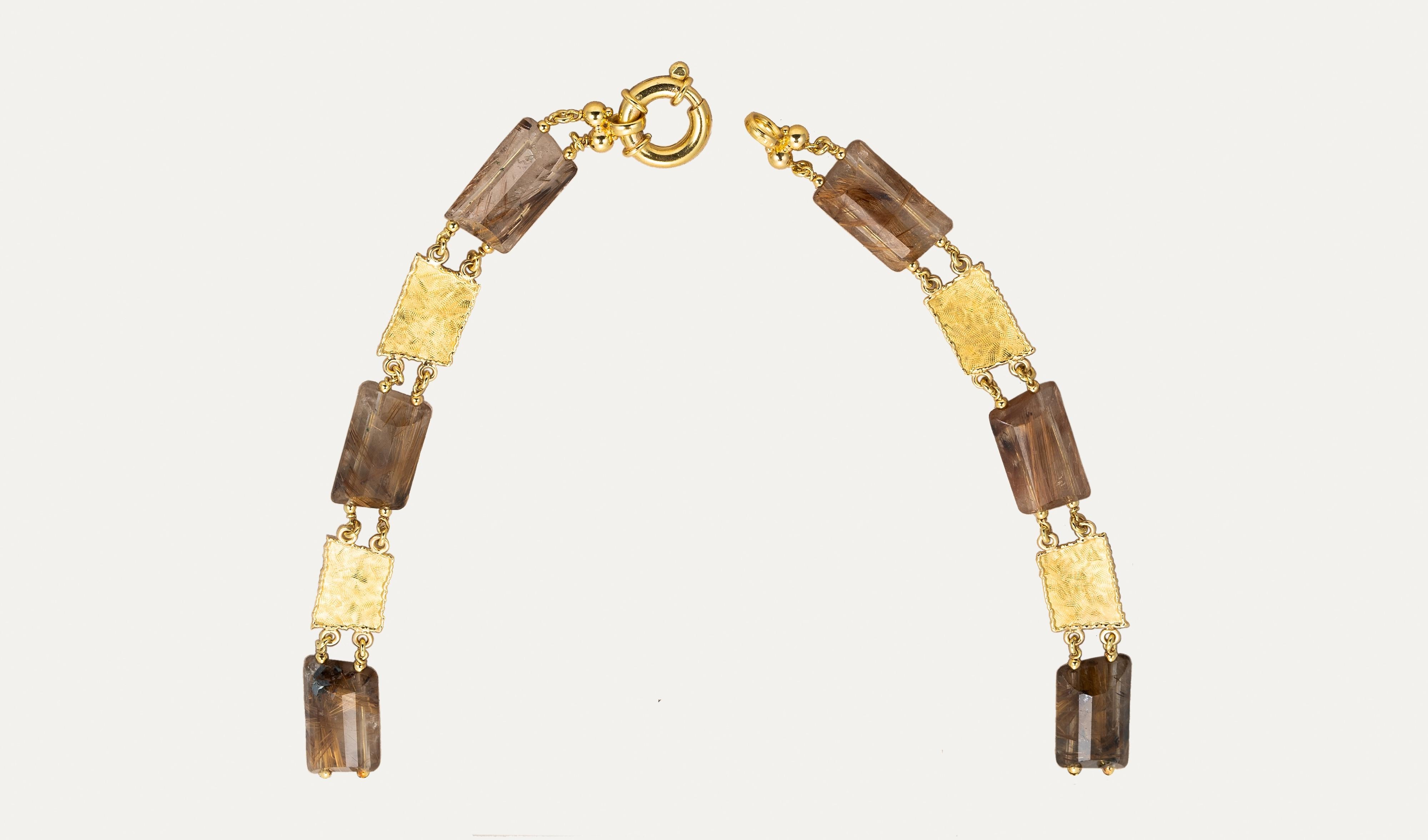 Ce collier en or jaune au quartz rutilé célèbre l'équilibre harmonieux entre la beauté naturelle et l'artisanat raffiné. Fabriquée à la main en or jaune, la pièce présente une séquence de pierres précieuses rectangulaires en quartz rutile, chacune