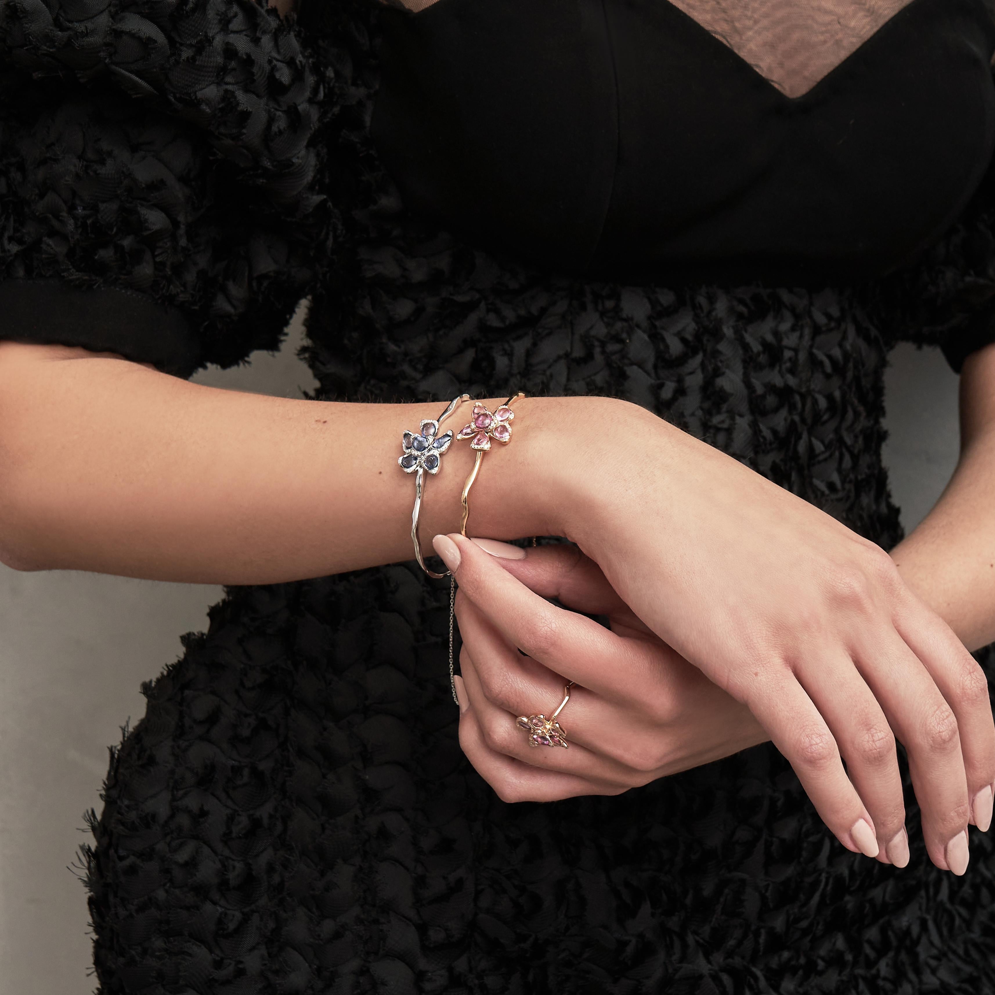 A delicate masterpiece of craftsmanship, this white Gold Petal Bangle embodies elegance and femininity. Designed with an organic, sculptural form, the bracelet features a stunning floral motif at its center, adorned with  Blue sapphires that radiate