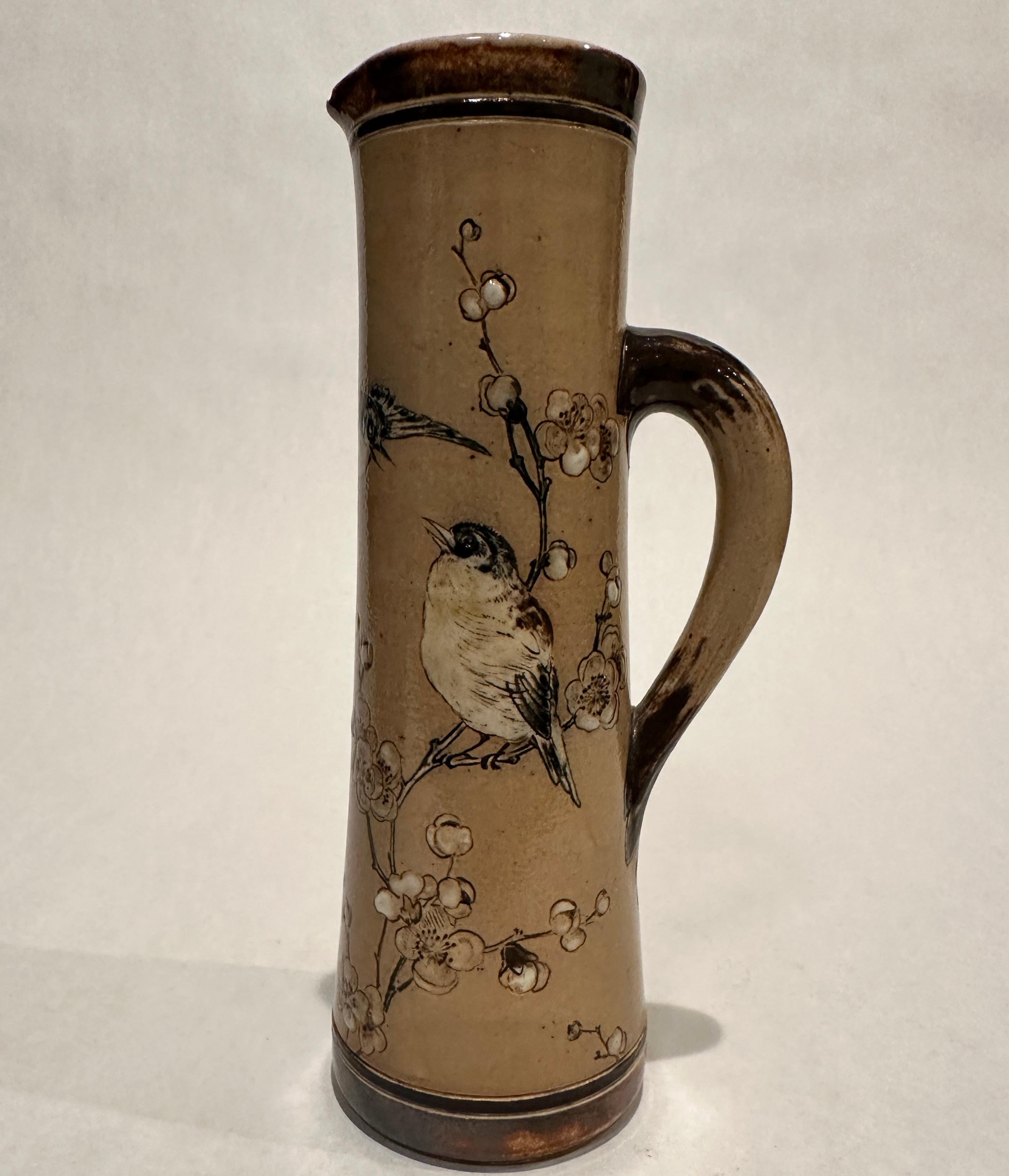 Beautiful pitcher decorated with small birds and butterfly among branches of cherry blossoms. Tan ground with shades of brown and whites. Incised RW Martin & Bros, London & Southall, 3-1886.