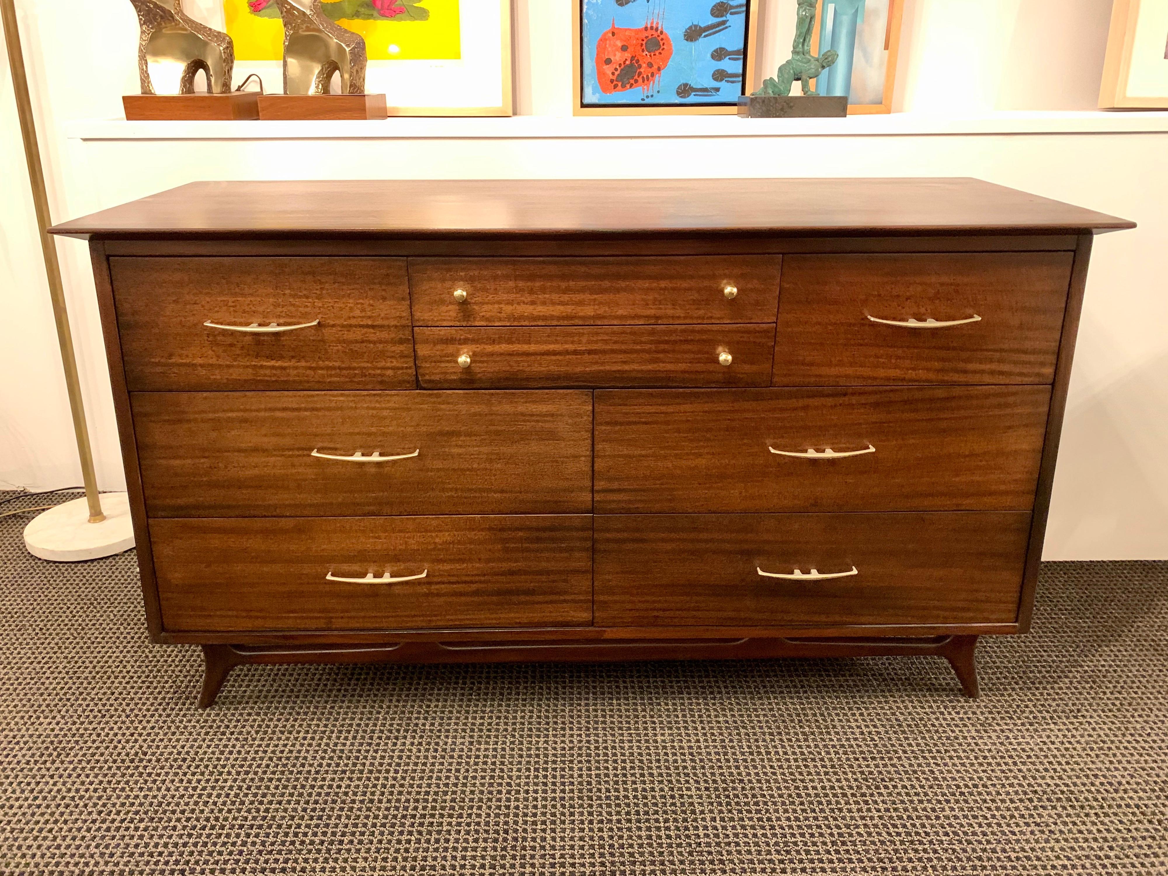 Beautifully design, this sculptural angled dresser in dark walnut finish with muted brass hardware. Many drawers for storage and in real fine vintage condition.