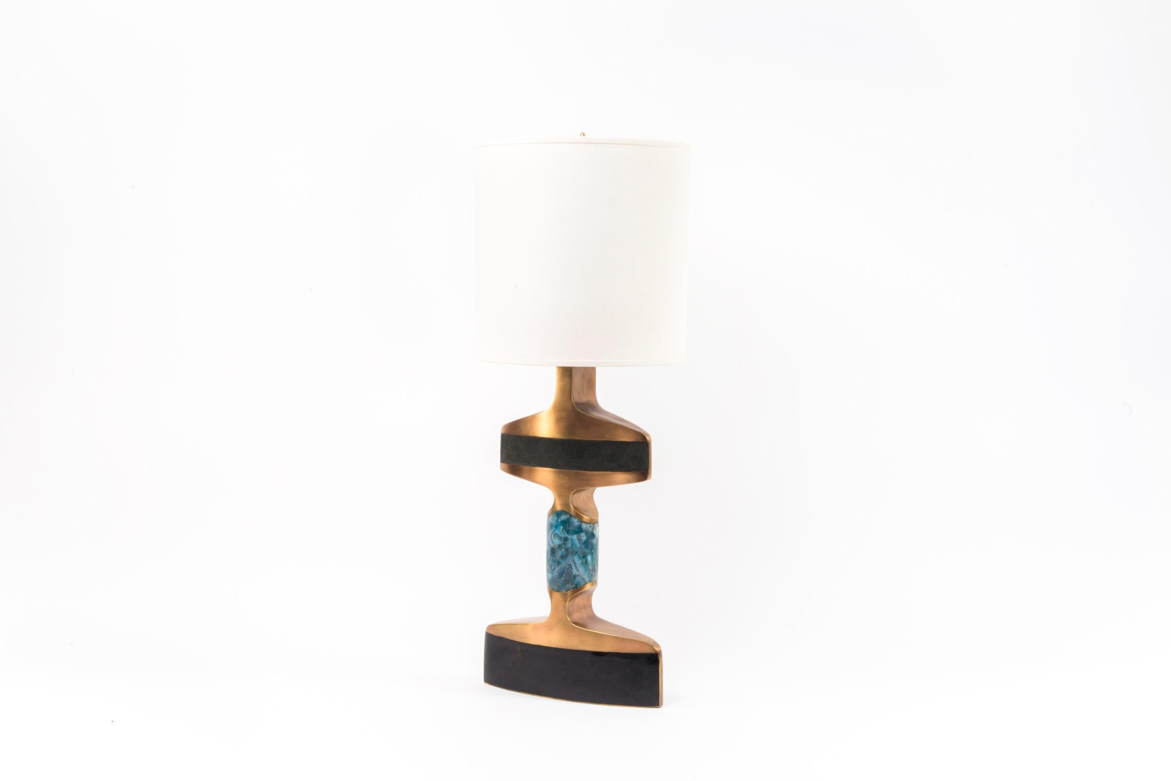 The Carmen Table Lamp is an elegant and sculptural piece that will light up your space with it’s exotic details. Inlaid in 3 different materials: coal black shagreen, black pen shell and blue agate and finished with bronze-patina brass accents. The