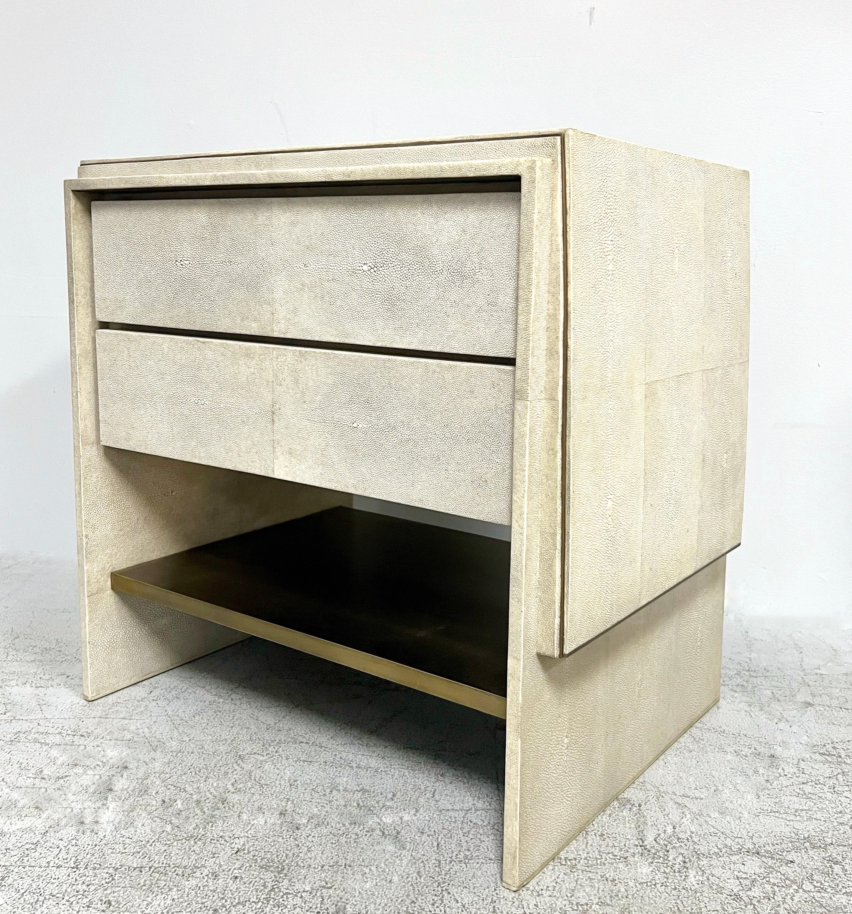 A single bedside table in cream shagreen and bronze by R$Y Augosti. Two drawers and a bronze shelf. Bronze detail on edges. Signed with plaque on underside of shelf.