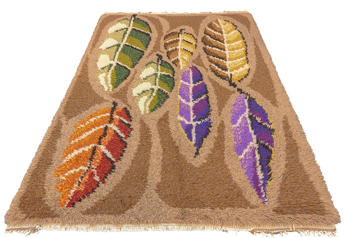 This vintage Scandinavian Rya rug presents a bold and whimsical abstract leaf motif that immediately evokes the charm of mid-century modern design. Woven in a lush, high-pile wool typical of traditional Rya craftsmanship, the rug is both a visual