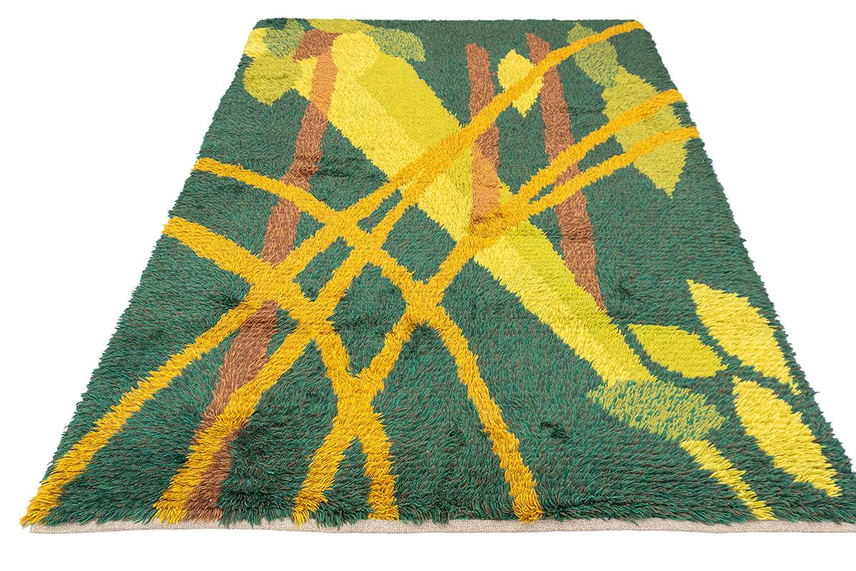 This striking Scandinavian Rya rug, measuring 199 × 135 cm, is a lush embodiment of mid-century modern artistry with a bold green-centric palette. Designed in the characteristic deep-pile style of traditional Rya weaving, it combines luxurious
