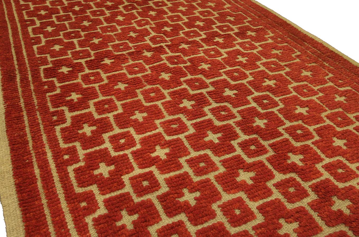 Ce tapis Rya mesure 124 x 202 cm et présente un motif géométrique dans des tons vibrants de rouge et de beige. Les motifs répétés créent un design structuré mais visuellement dynamique, ce qui en fait un complément polyvalent pour les intérieurs