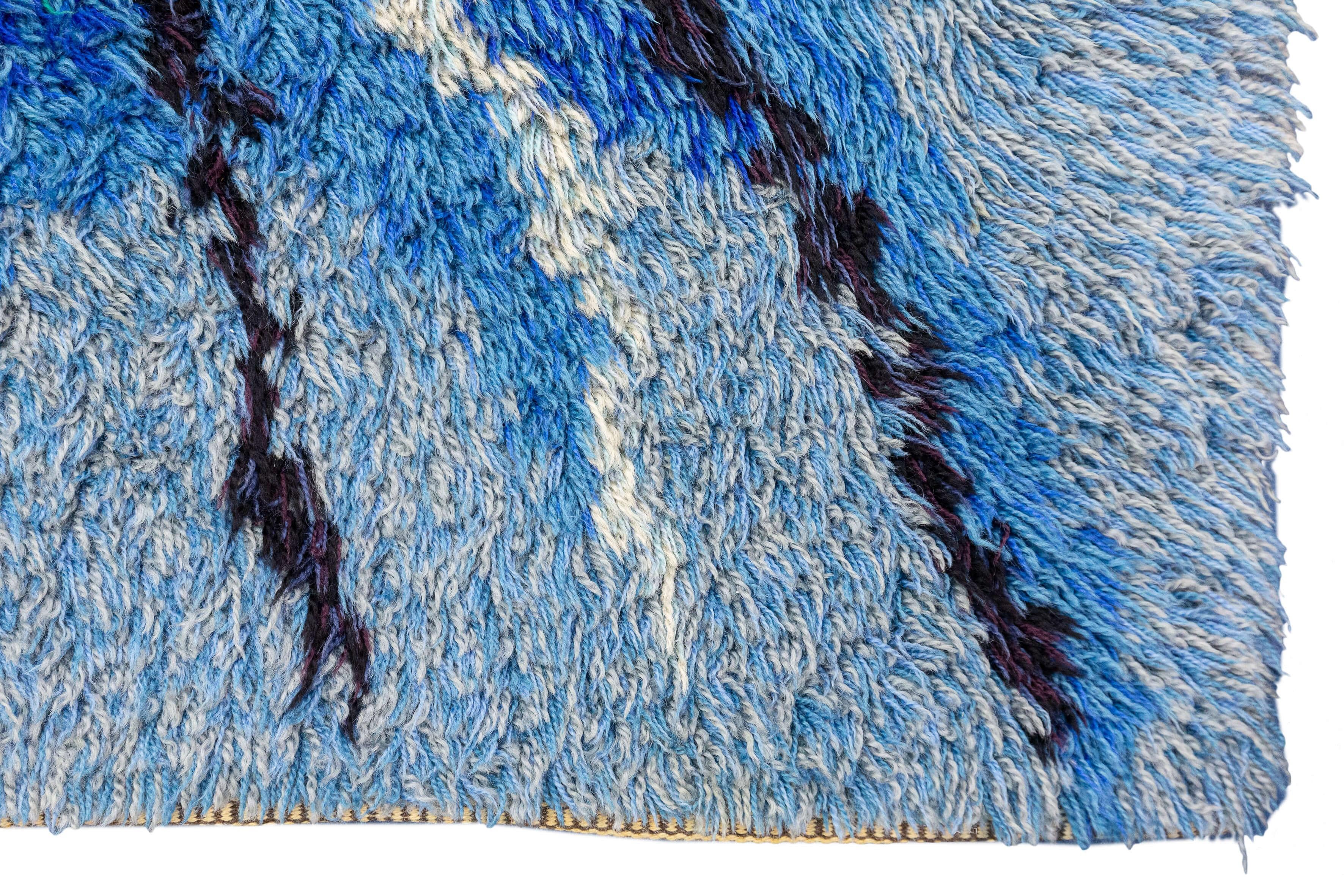 Der schwedische Teppich Rya mit seinem abstrakten Muster in Violett- und Blautönen ist ein wirklich einzigartiges und besonderes Stück, das jedem Raum einen lebendigen und modernen Touch verleiht. Die Kombination von abstrakten Mustern schafft ein