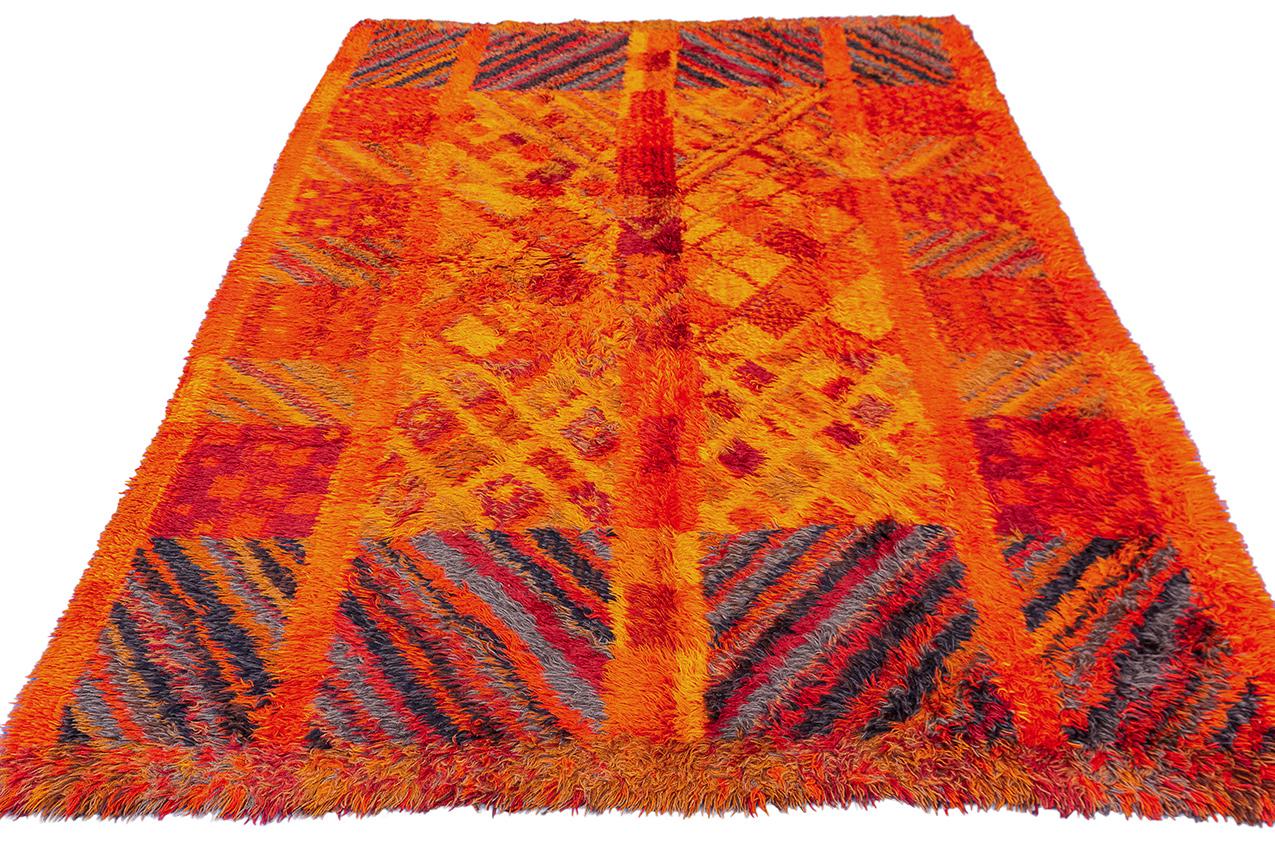 Ce tapis suédois Rya, avec ses couleurs vibrantes d'orange et de rouge et son design coloré, est une pièce unique et spéciale qui rayonne de chaleur et de flair artistique. La combinaison de ces teintes audacieuses crée une ambiance visuellement