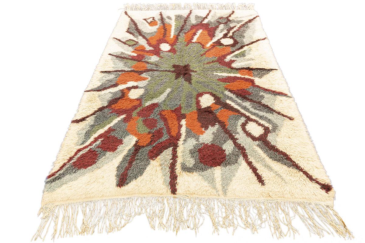 Vintage Rya Rug with Abstract Starburst Design – 189 × 132 cm
This striking Scandinavian Rya rug captures the eye with an explosive abstract design reminiscent of a starburst or energetic floral bloom. Rendered in a vivid palette of earthy rust,